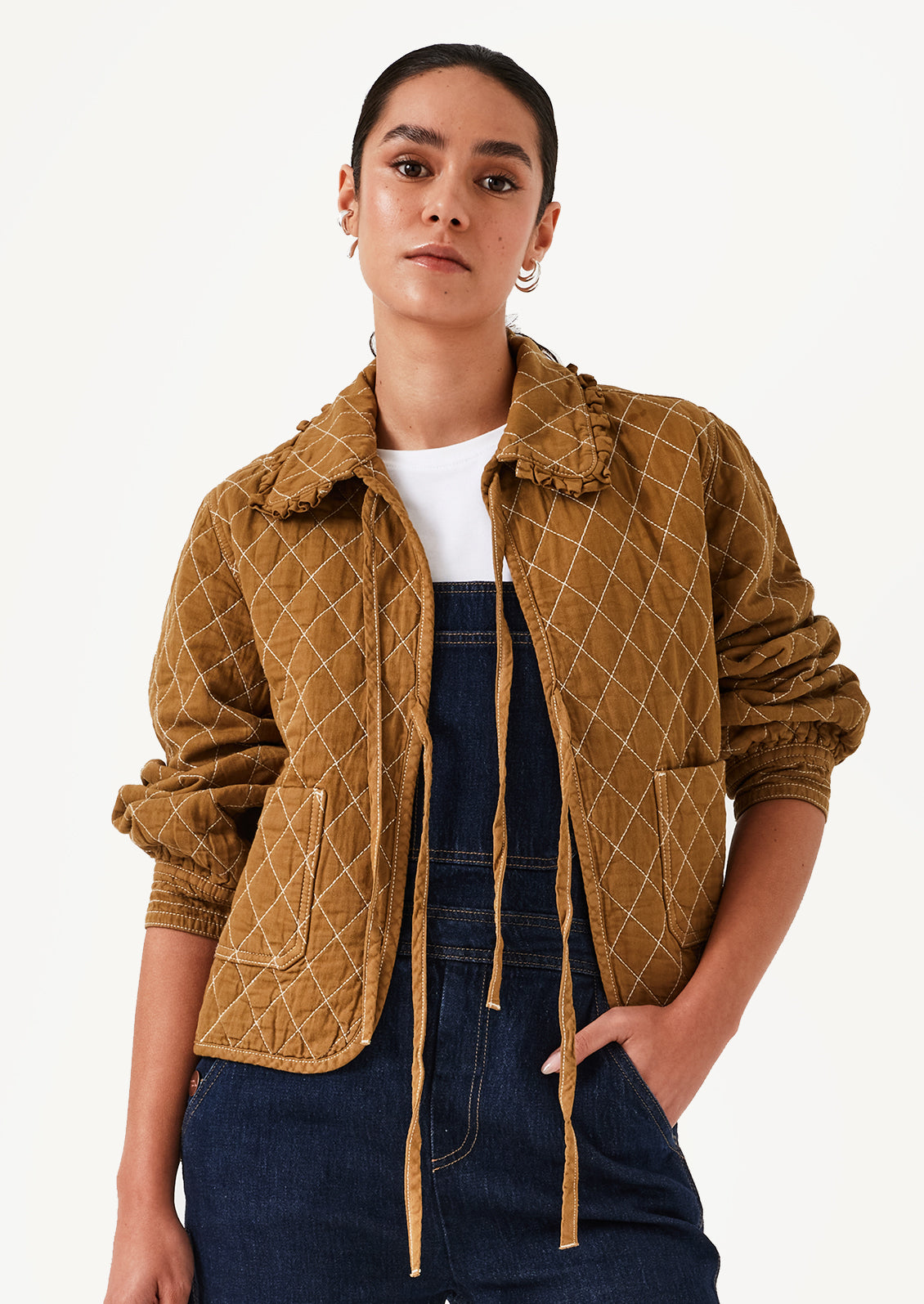 A woman wearing an ochre colored jacket with diamond quilting and bow tie front.