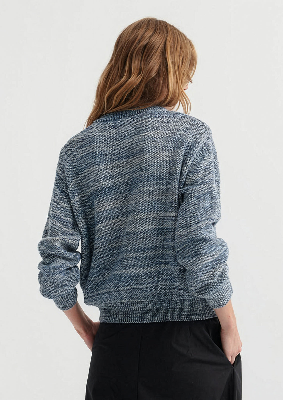 Person wearing a blue knitted sweater on a white background