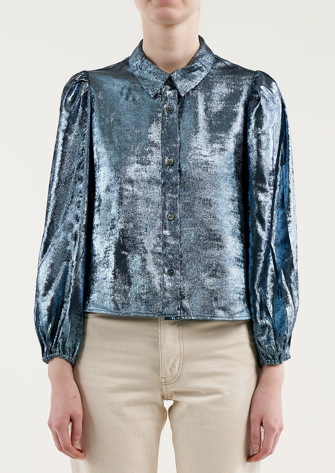 A woman wearing a metallic blue collared blouse.