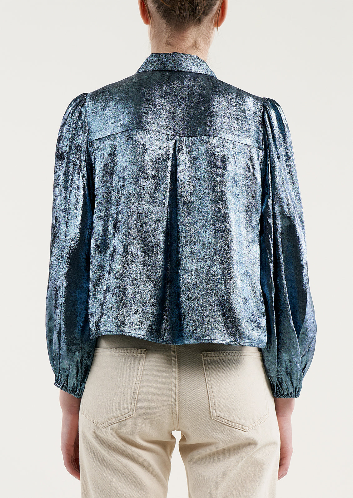 A woman wearing a metallic blue collared blouse.