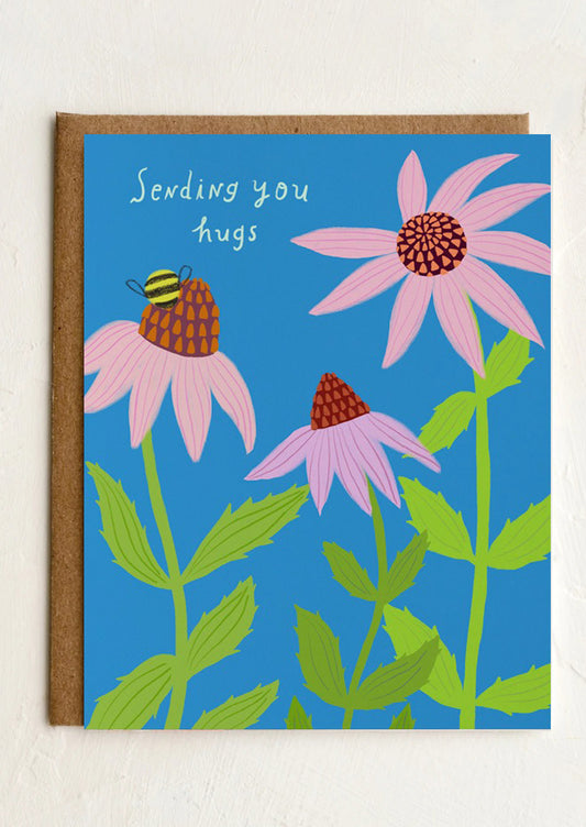 Card with pink flowers and a bee on a blue background, featuring the text 'Sending you hugs'.