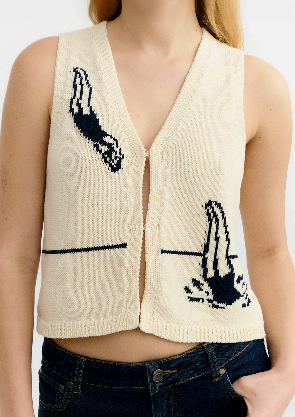 Beige cardigan with black designs worn by a person on a white background