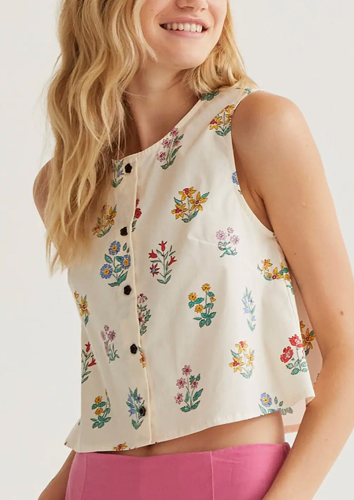 Woman wearing a sleeveless floral blouse with a white background