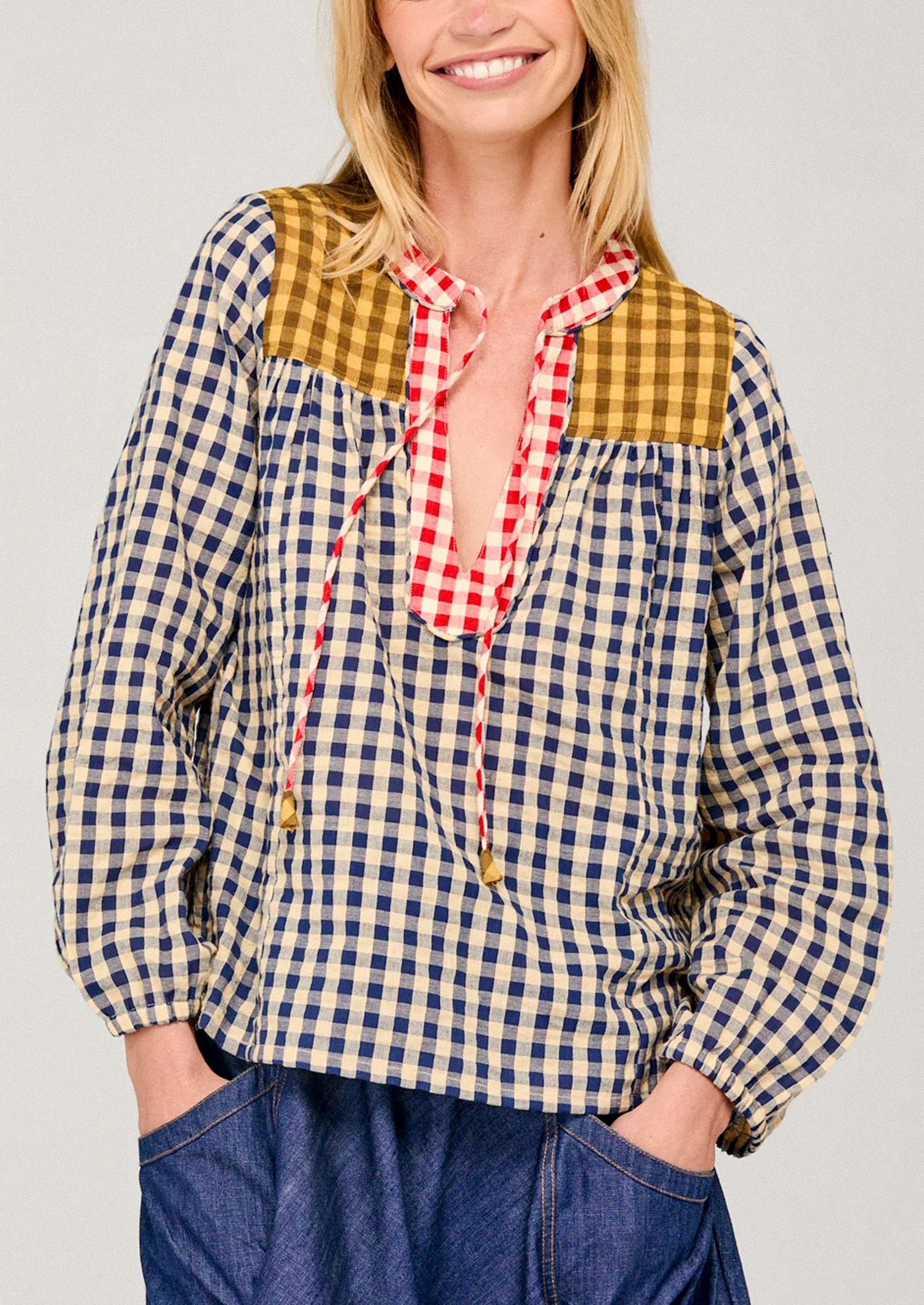 Woman wearing a checkered shirt with a red plaid collar against a plain background