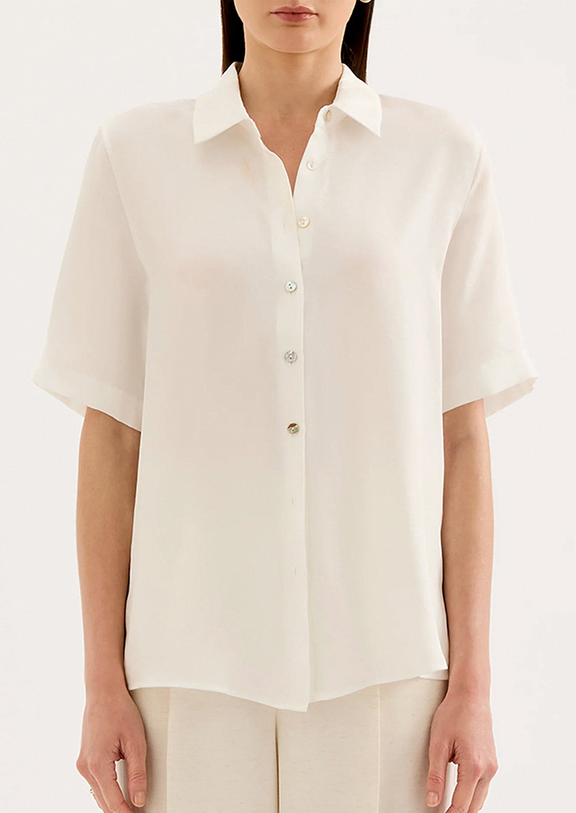 Person wearing a white button-up shirt on a plain background