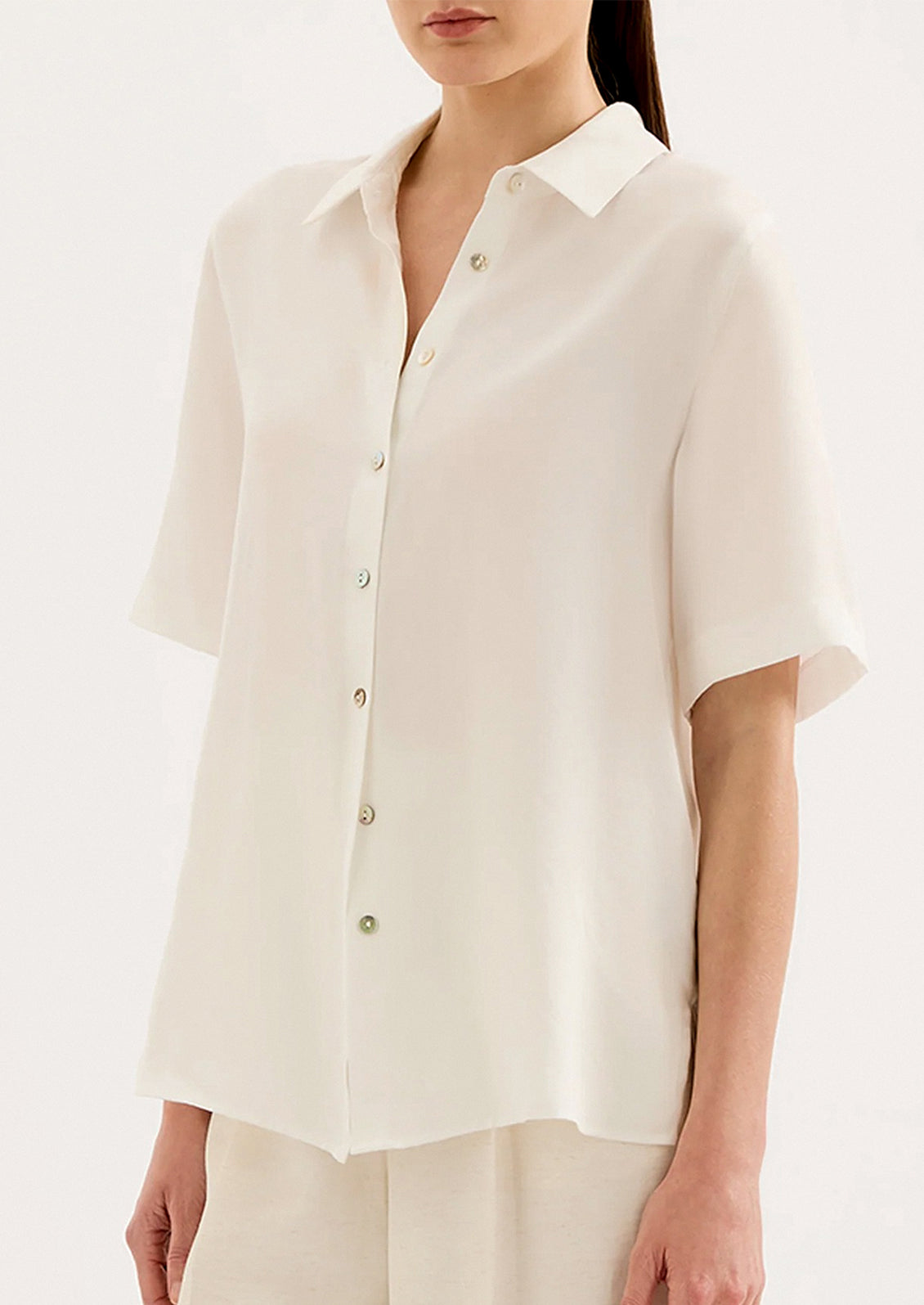 Woman wearing a white button-up shirt on a plain background