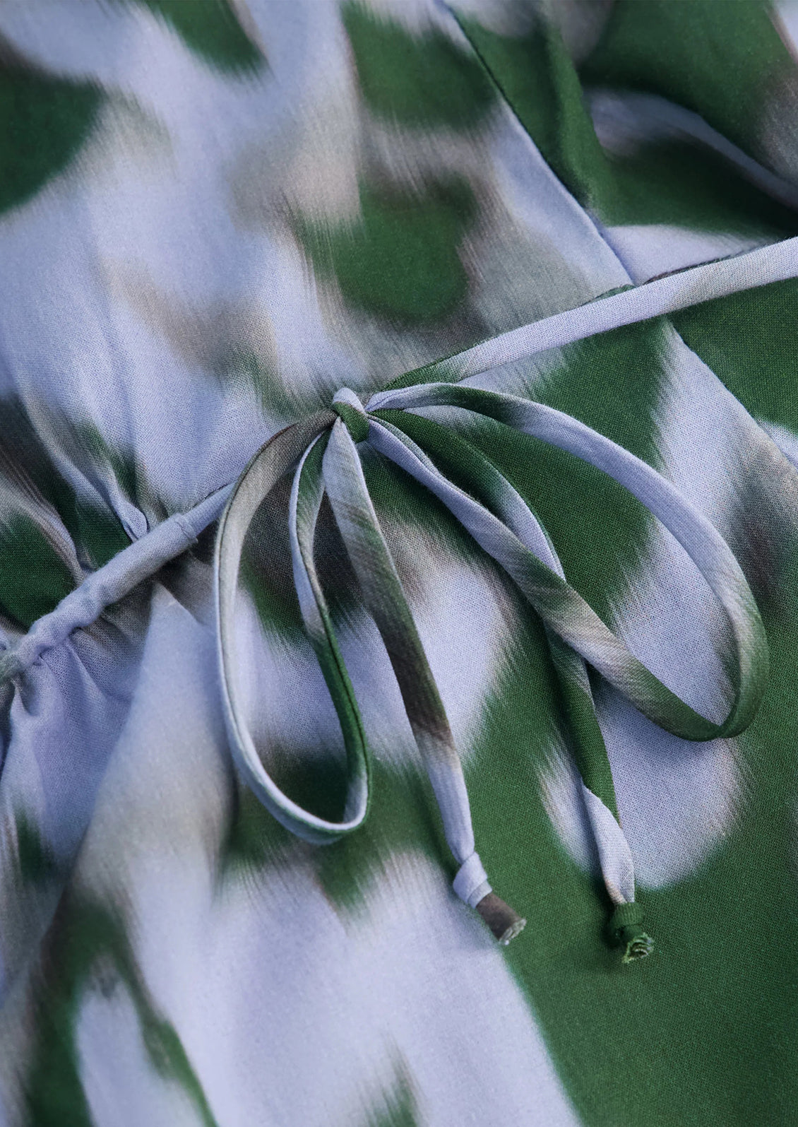 Close-up of a green and white patterned fabric with a branch.