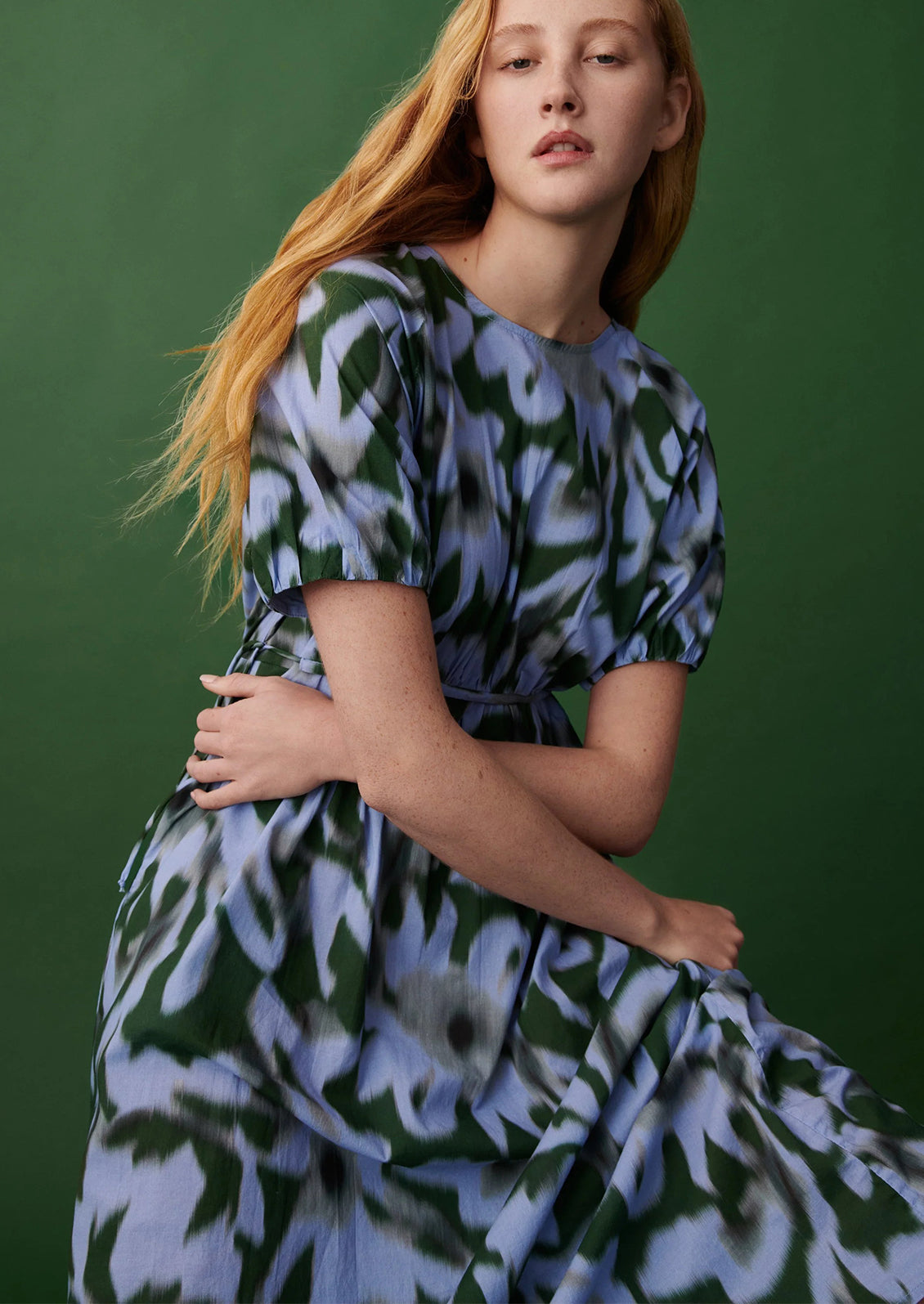 Woman wearing a floral dress against a green background