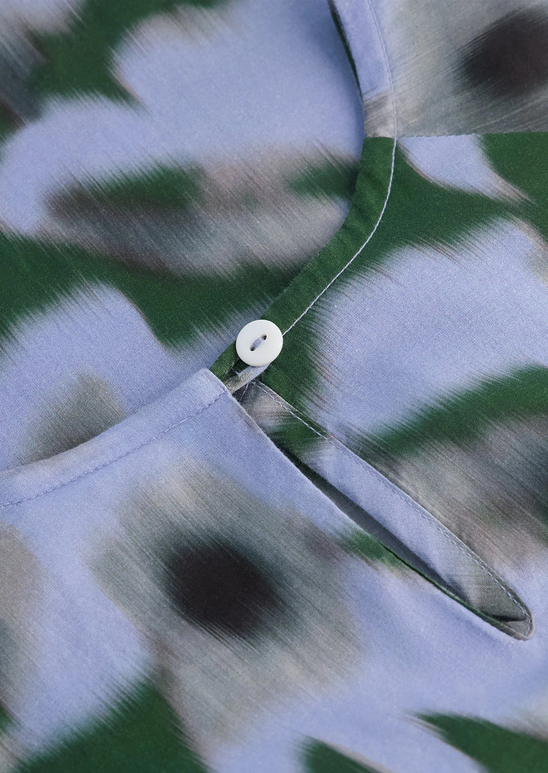 Close-up of a button on a patterned fabric with green, white, and black colors.