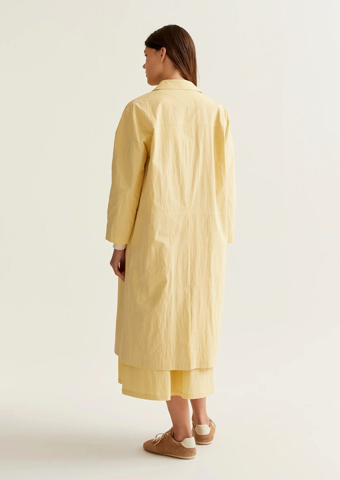 Person wearing a yellow long coat on a white background