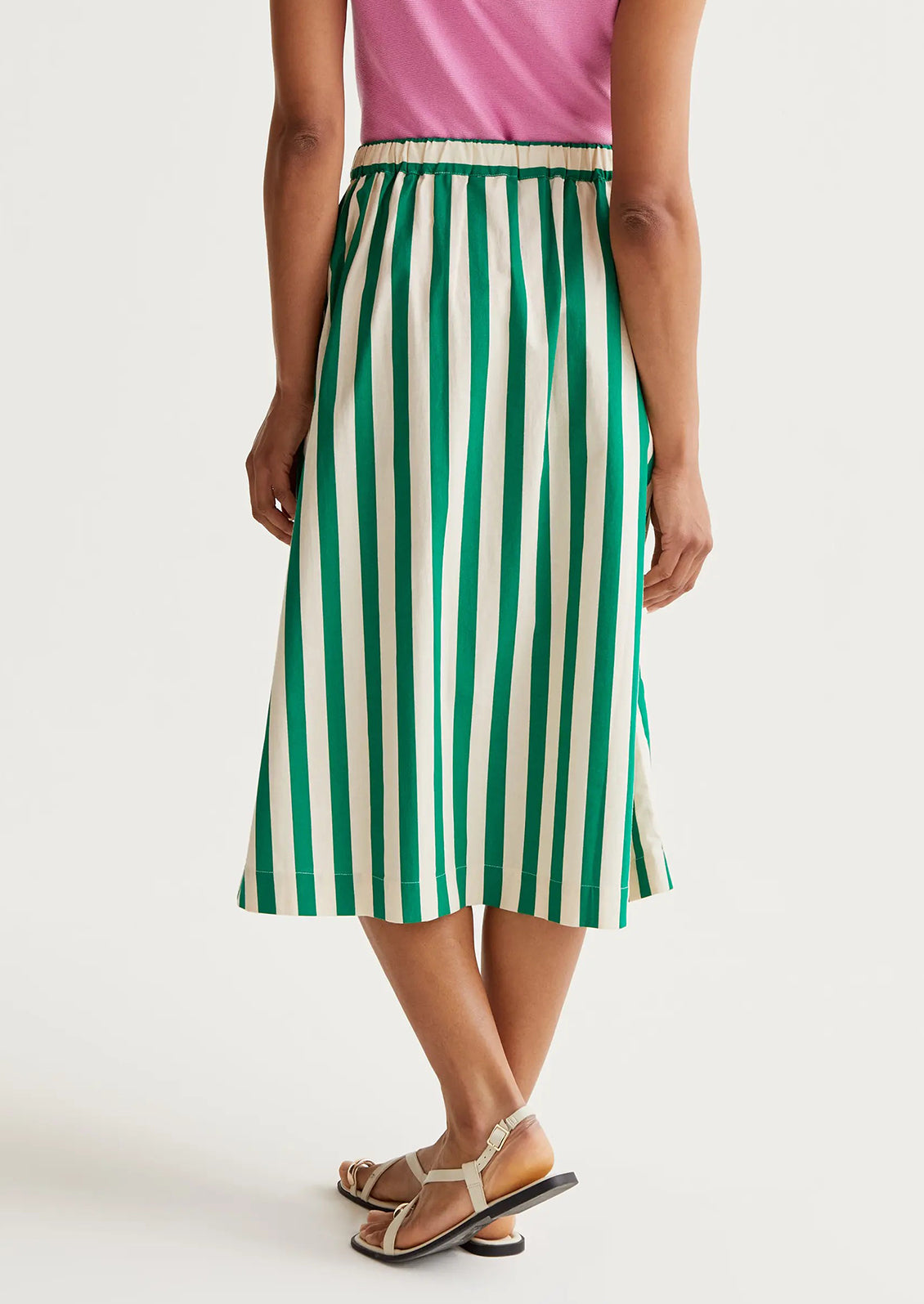 Person wearing a green and white striped skirt on a plain background