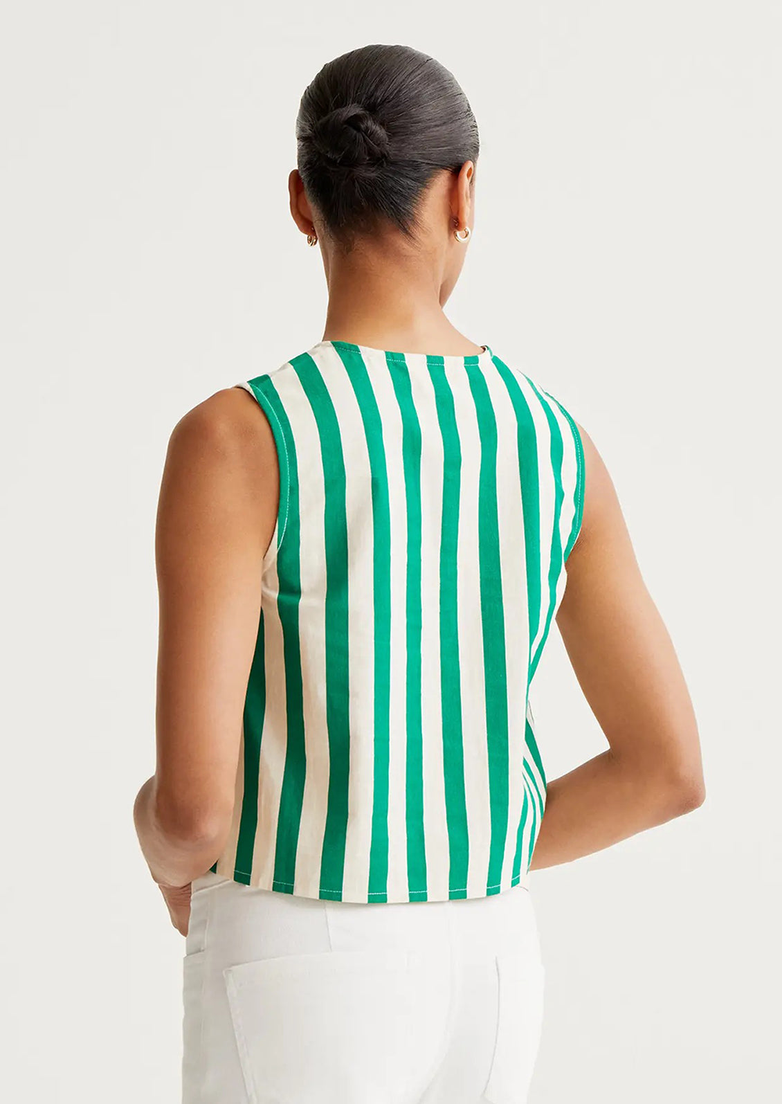 Woman wearing a green and white striped sleeveless top on a plain background