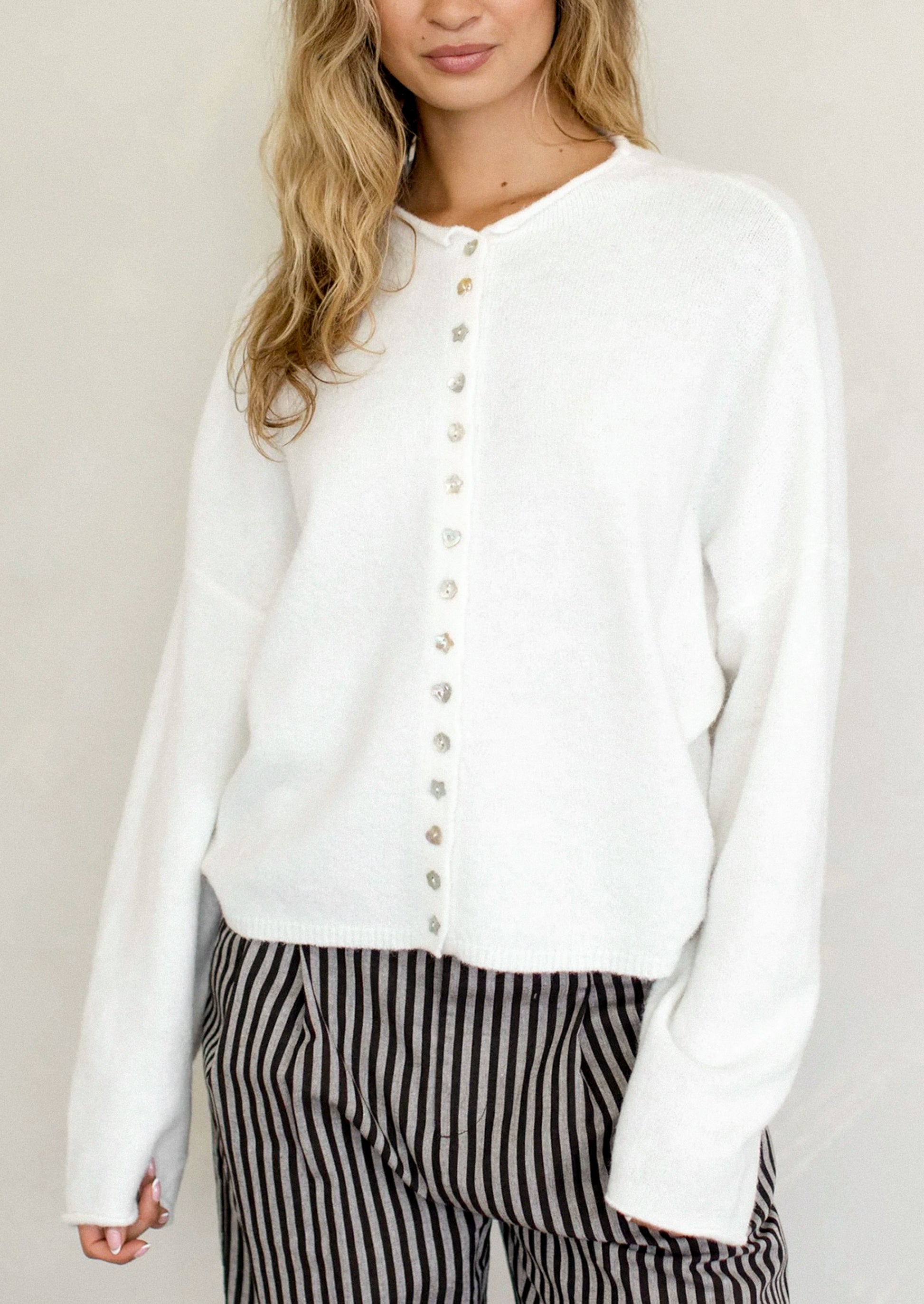 Person wearing a white button-up shirt with black and white striped pants against a plain background