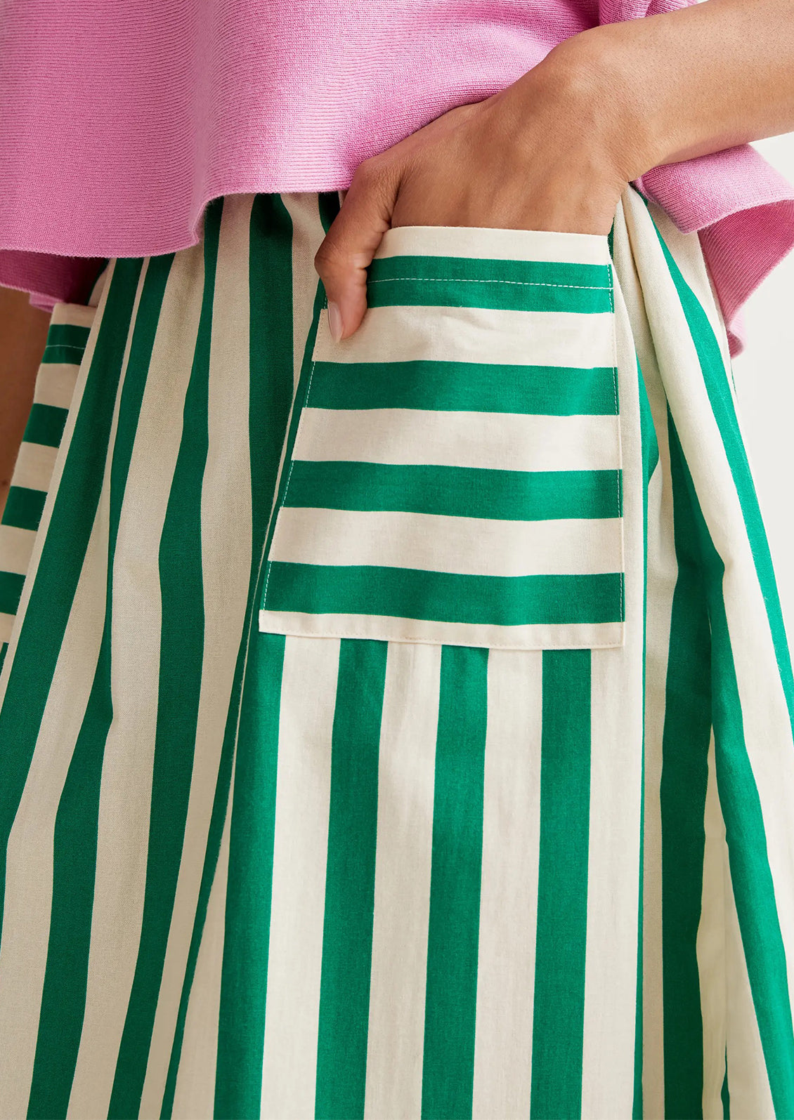 Green and white striped apron with a pink shirt worn by a person.