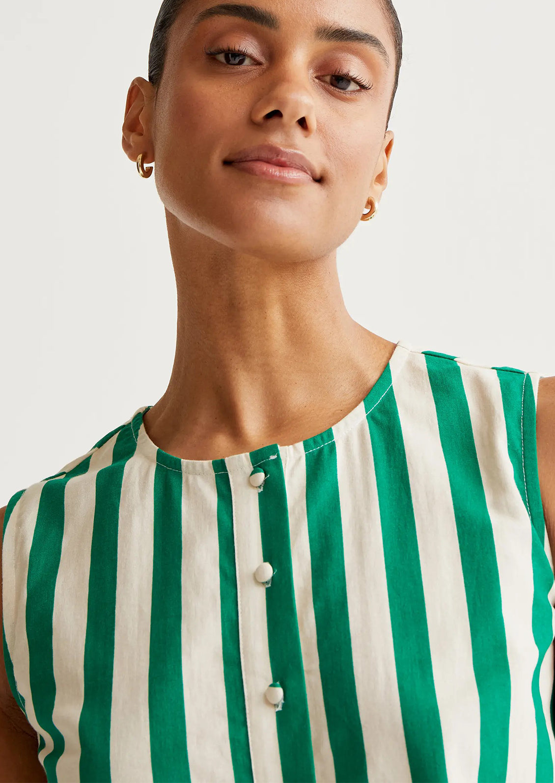Woman wearing a green and white striped shirt against a plain background