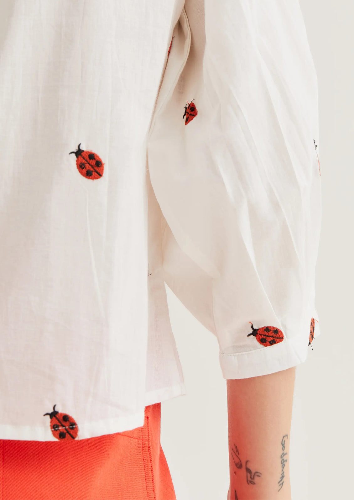 White shirt with ladybug patterns on a white background