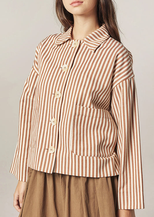 Woman wearing a brown and white striped shirt with a neutral background