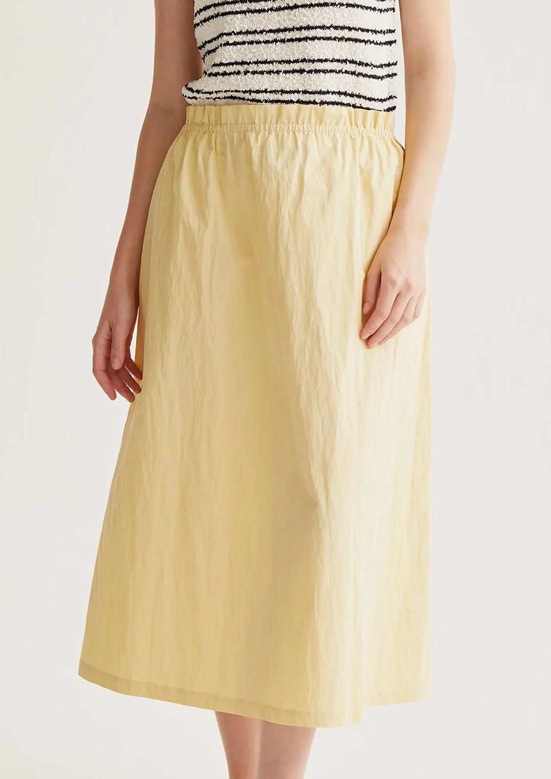 Person wearing a yellow skirt and striped top on a white background