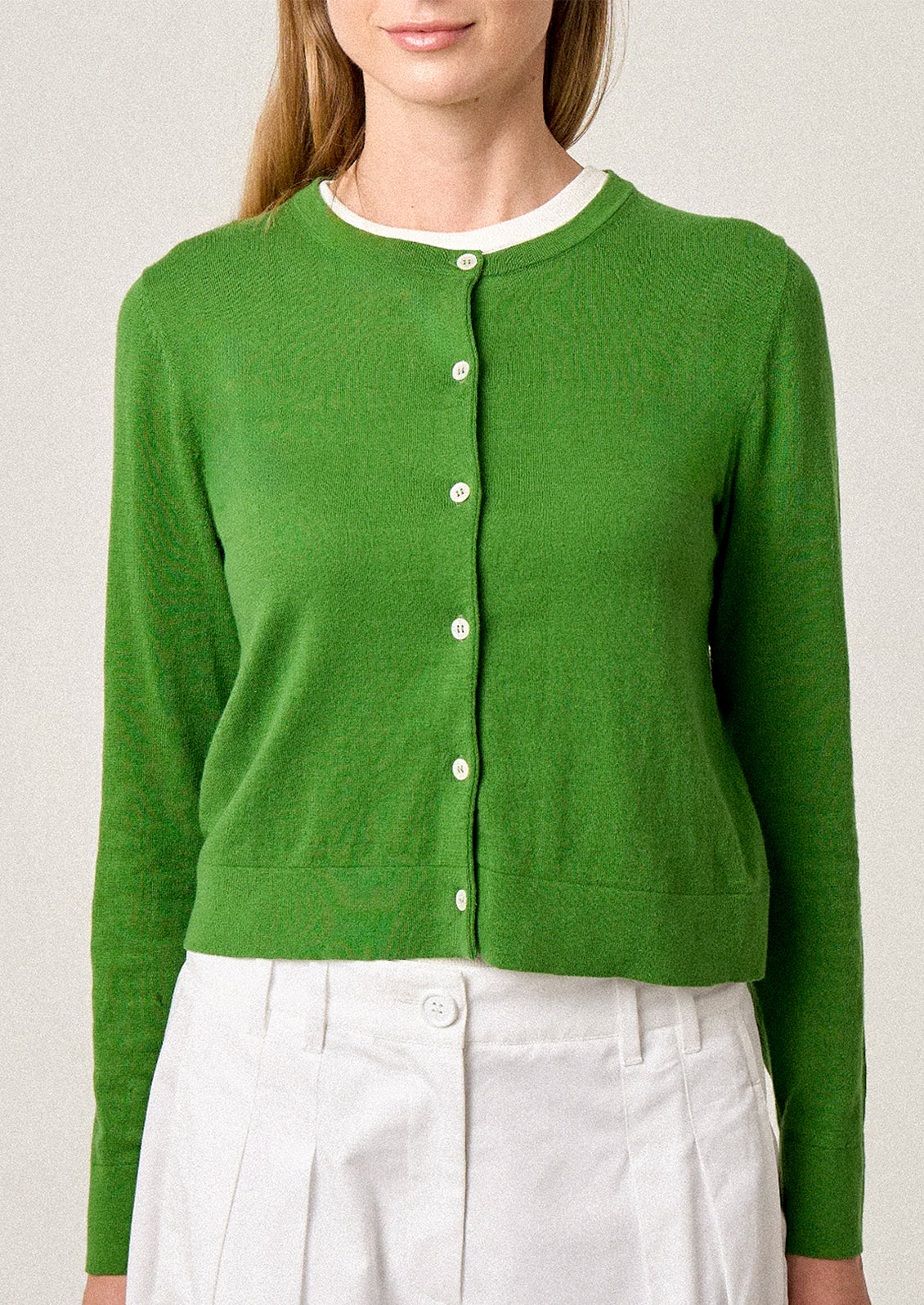 Green cardigan worn by a person on a plain background