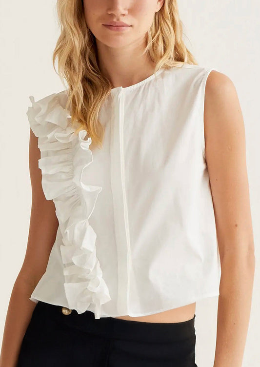 Woman wearing a white sleeveless top with ruffle details on a plain background