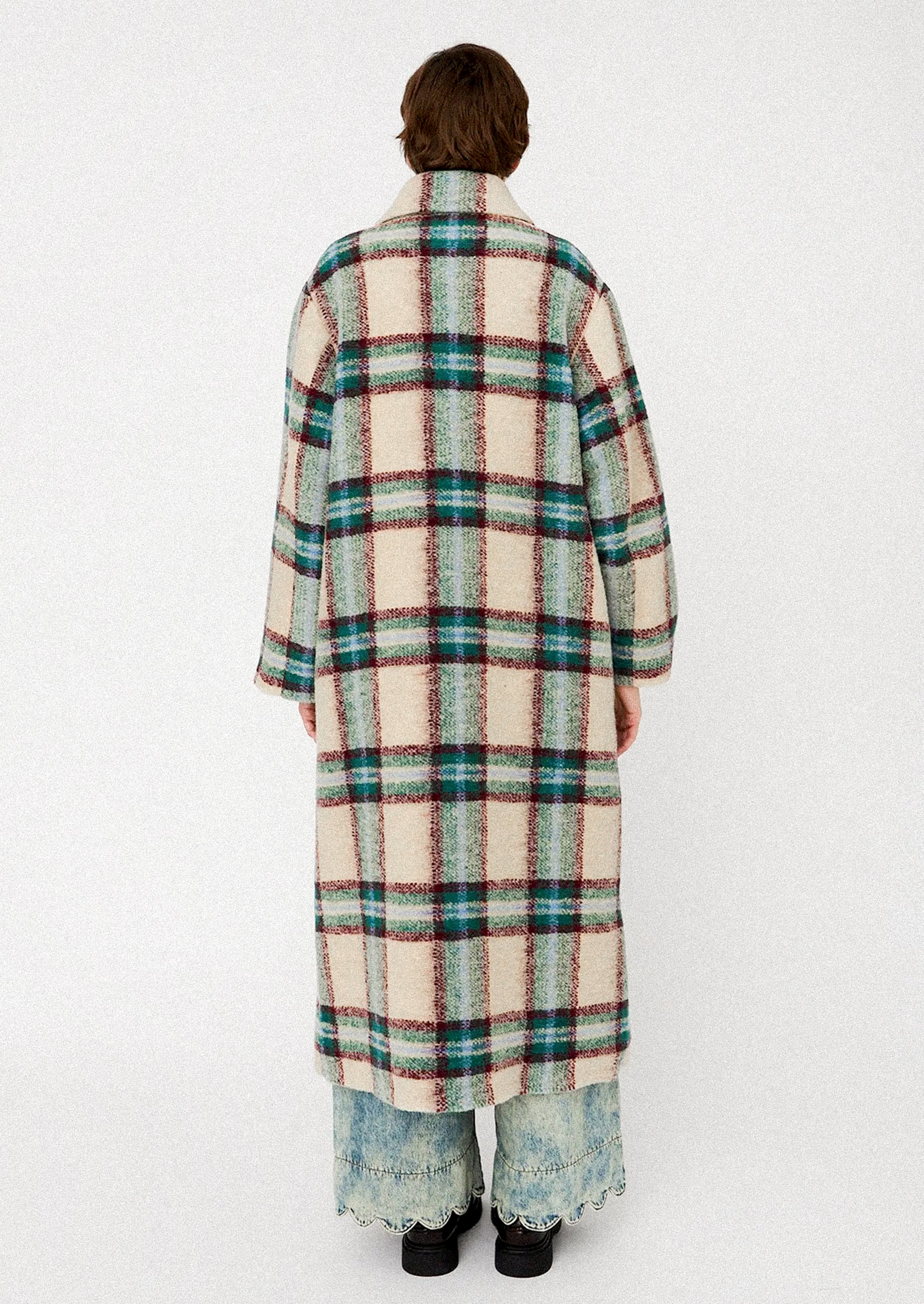 Person wearing a long plaid coat on a white background