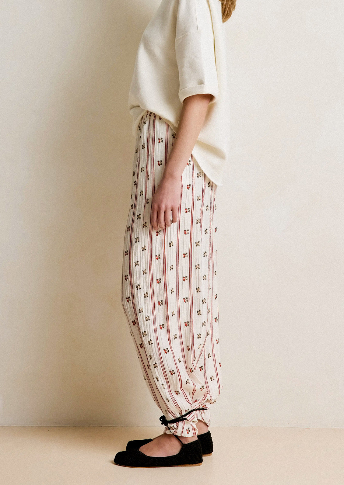 Person wearing a white top and patterned pants with a plain background