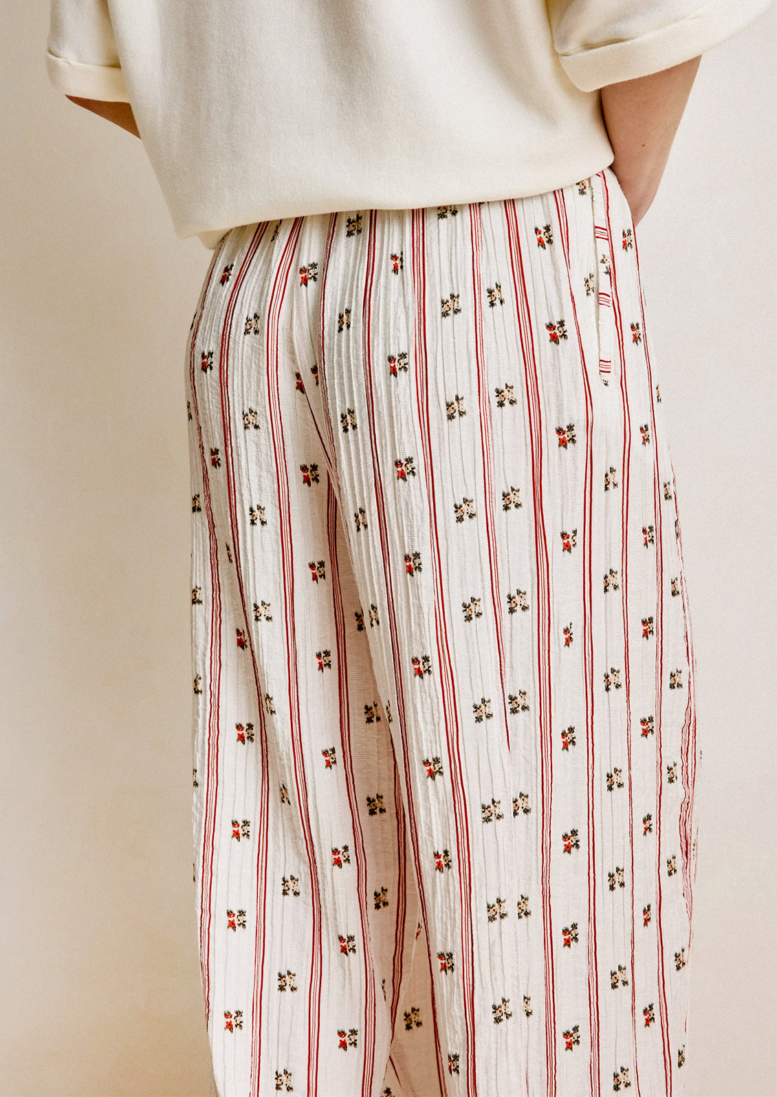 Person wearing a white top and patterned pants with small floral designs.