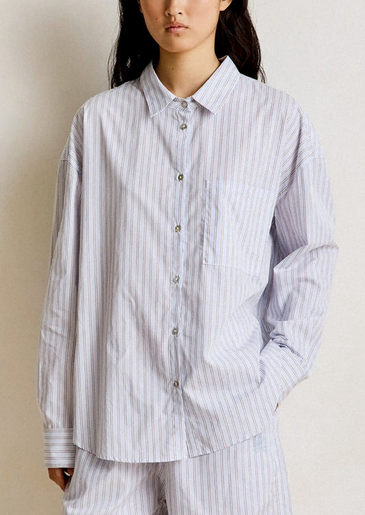 Person wearing a light blue and white striped shirt and pants on a plain background