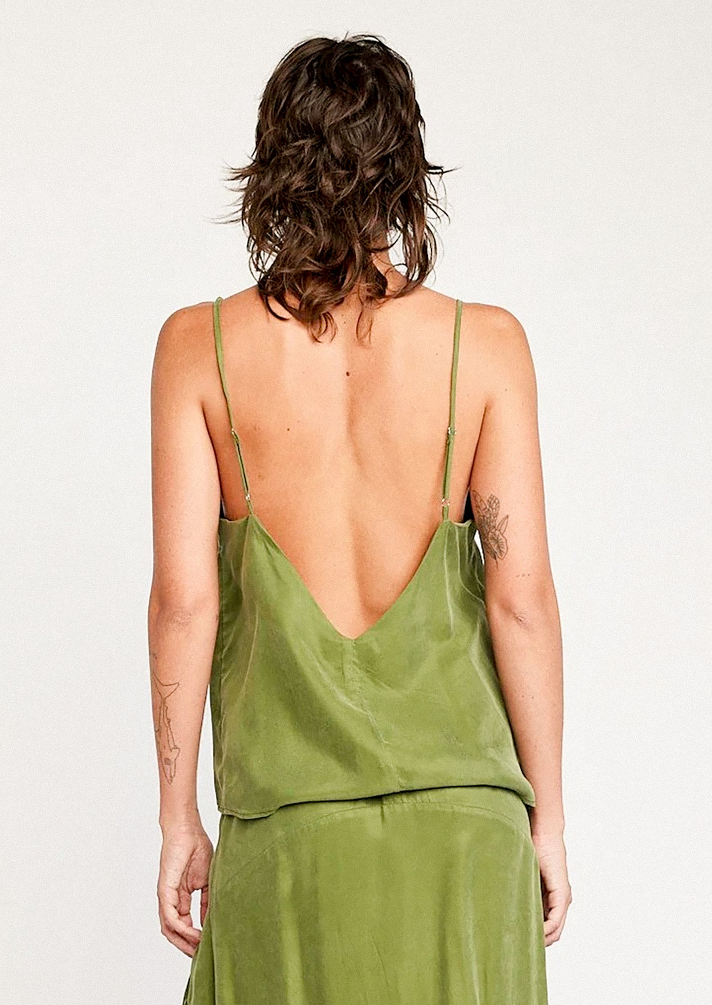 A person wearing a cupro camisole in kelp green.