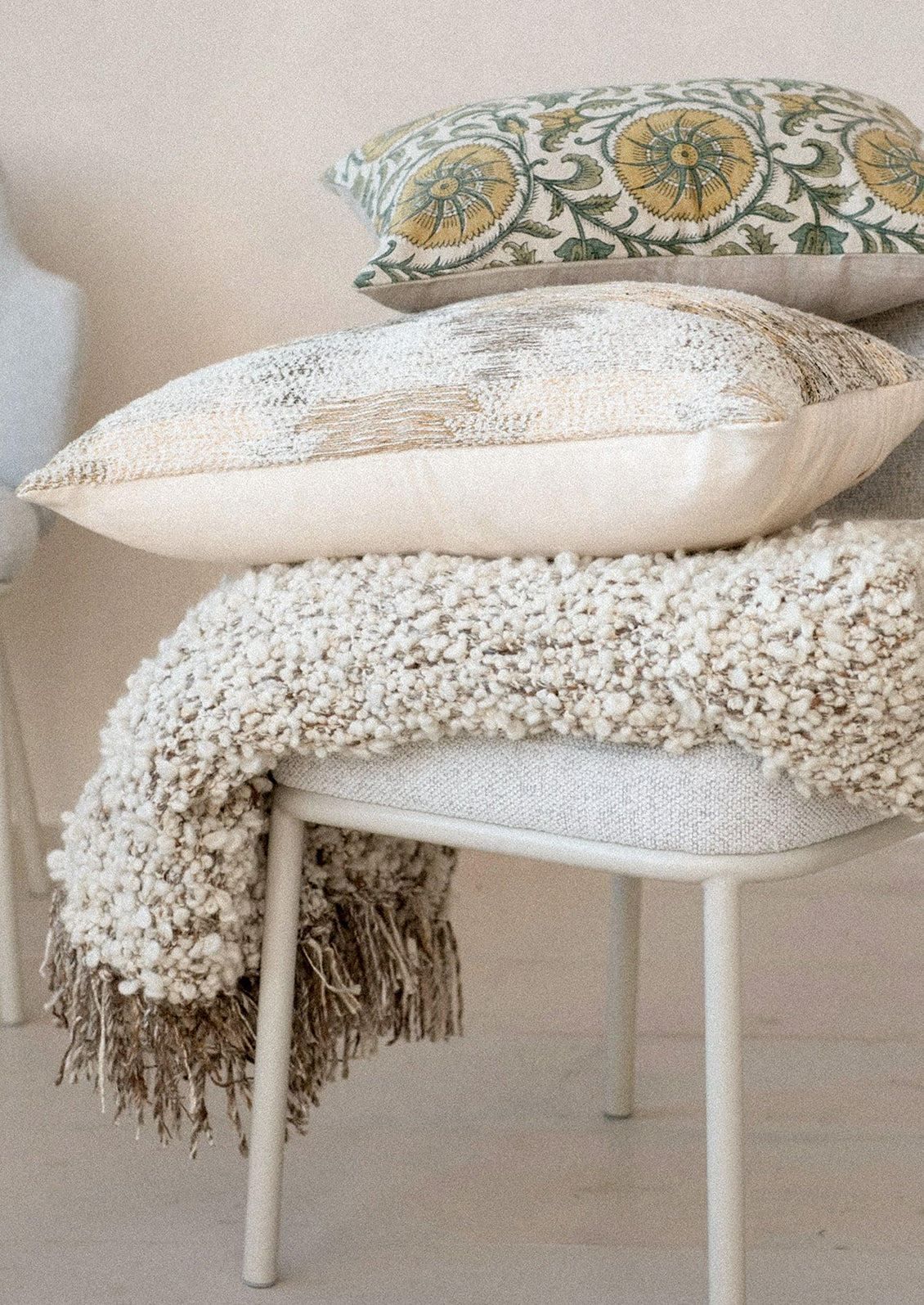 Decorative pillows and blanket on a chair with a neutral background
