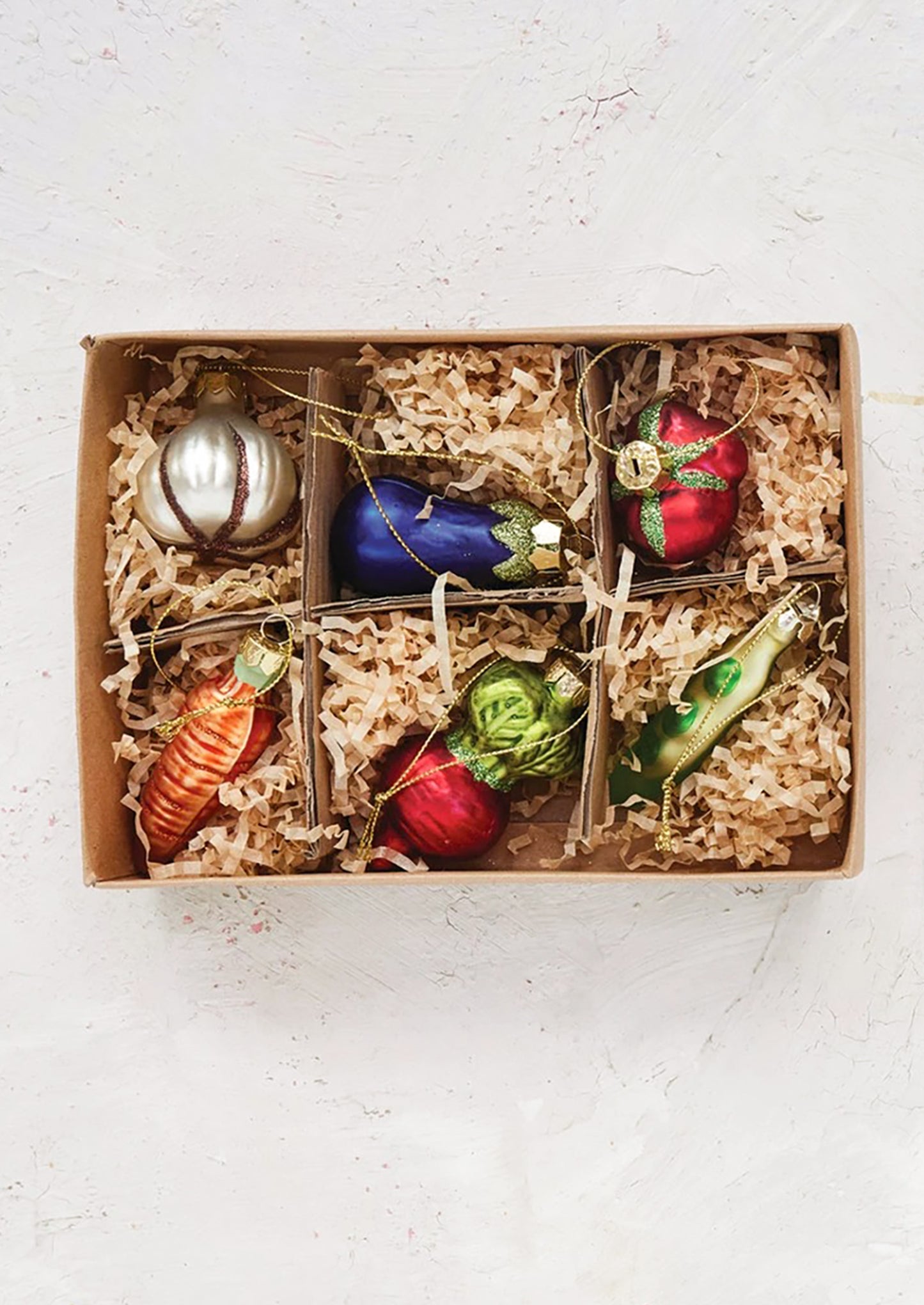Set of colorful glass vegetable-shaped ornaments in a gift box with crinkle paper.