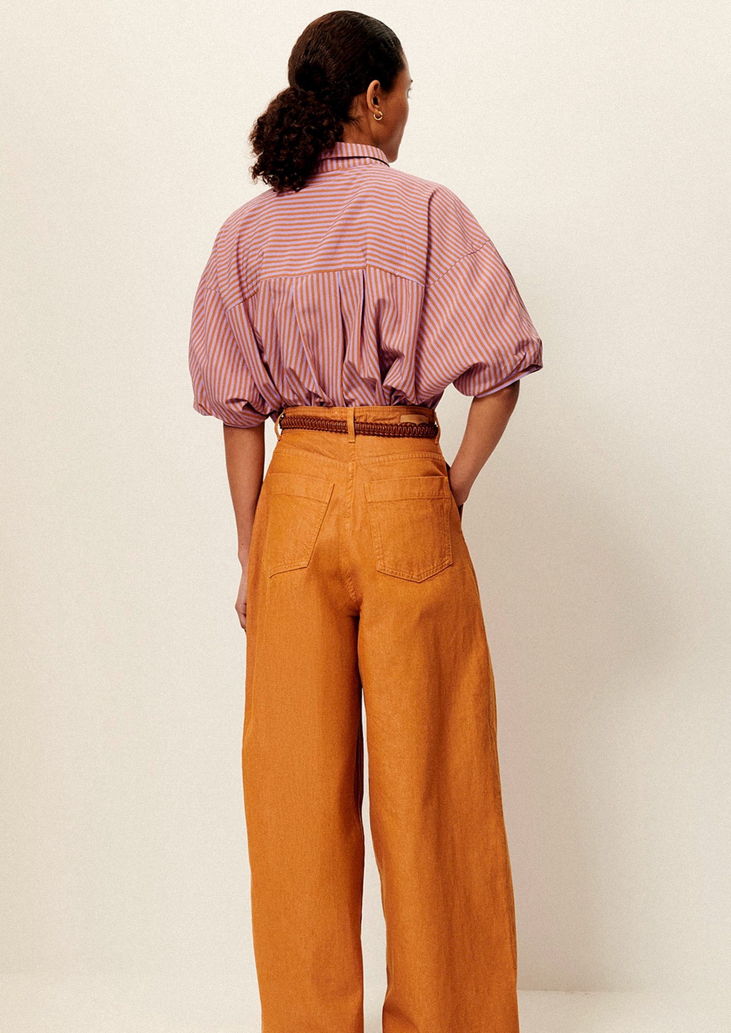 A woman wearing a short collared shirt in orange and purple stripes.
