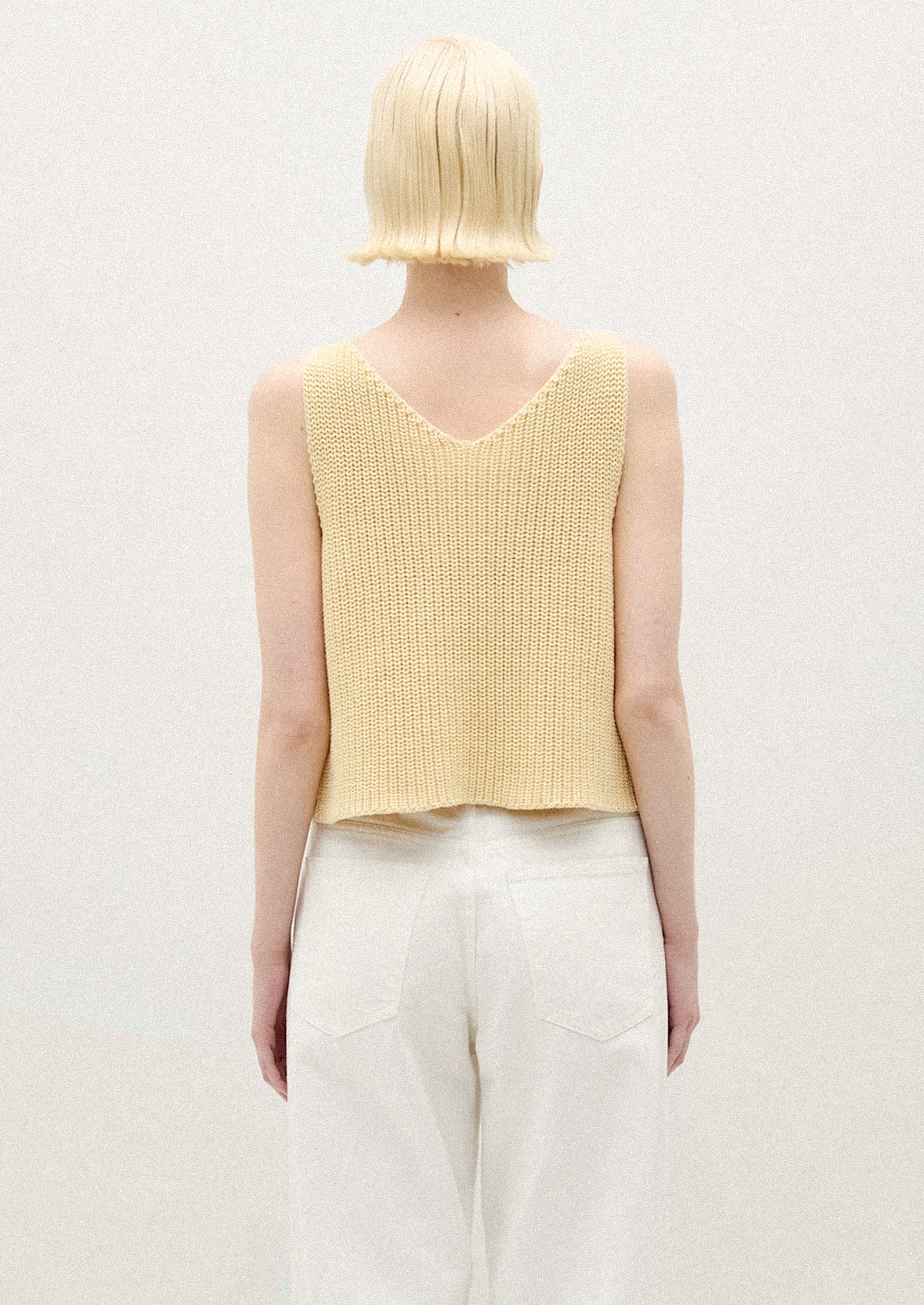 A person wearing a sleeveless knit vest in two tone yellow.