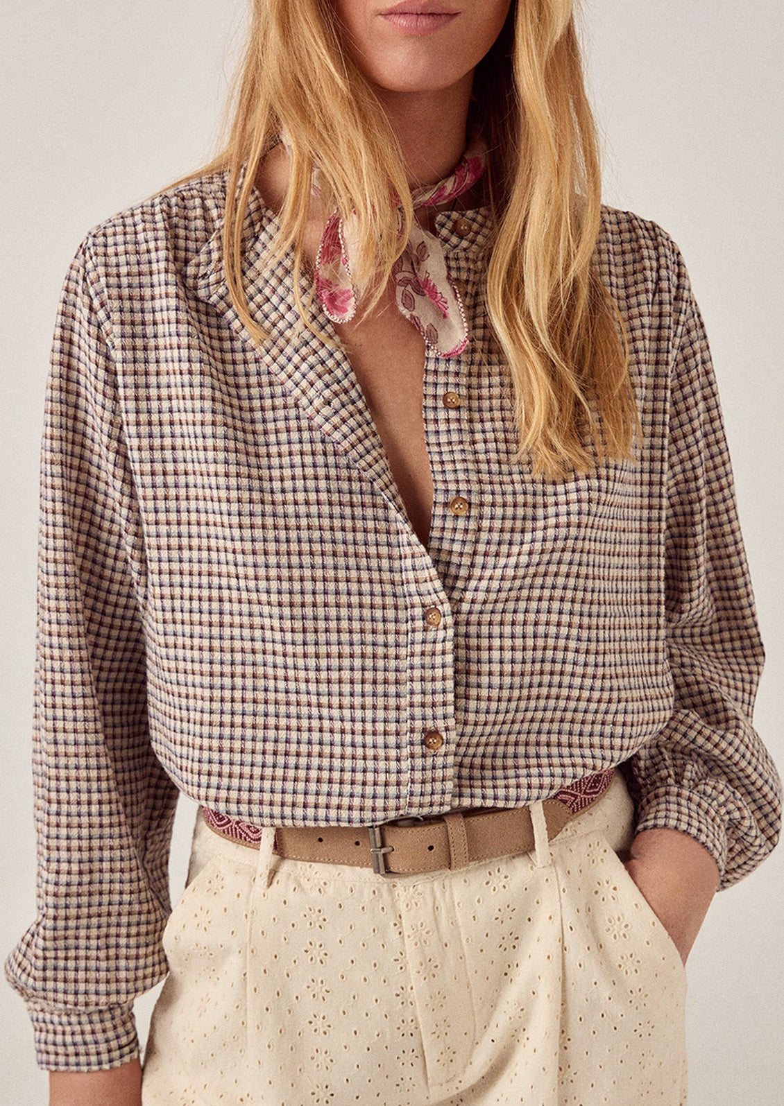 A person wearing a long sleeve blouse in brown check.