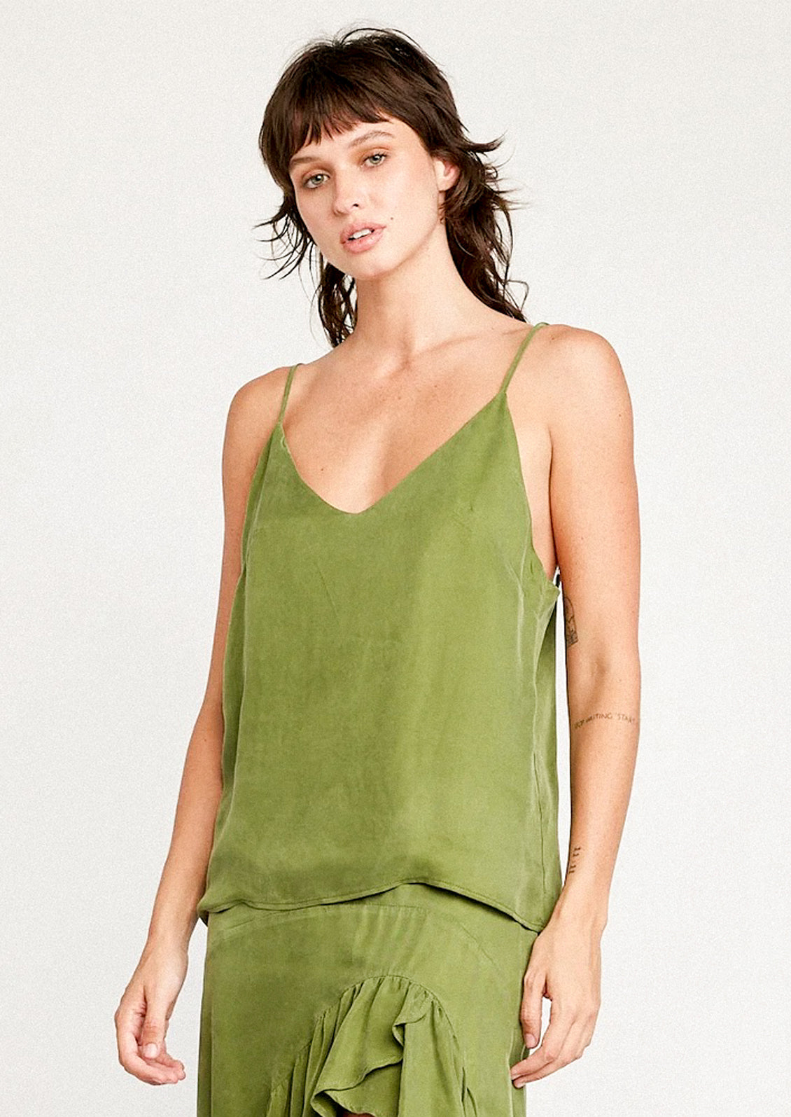 A person wearing a cupro camisole in kelp green.