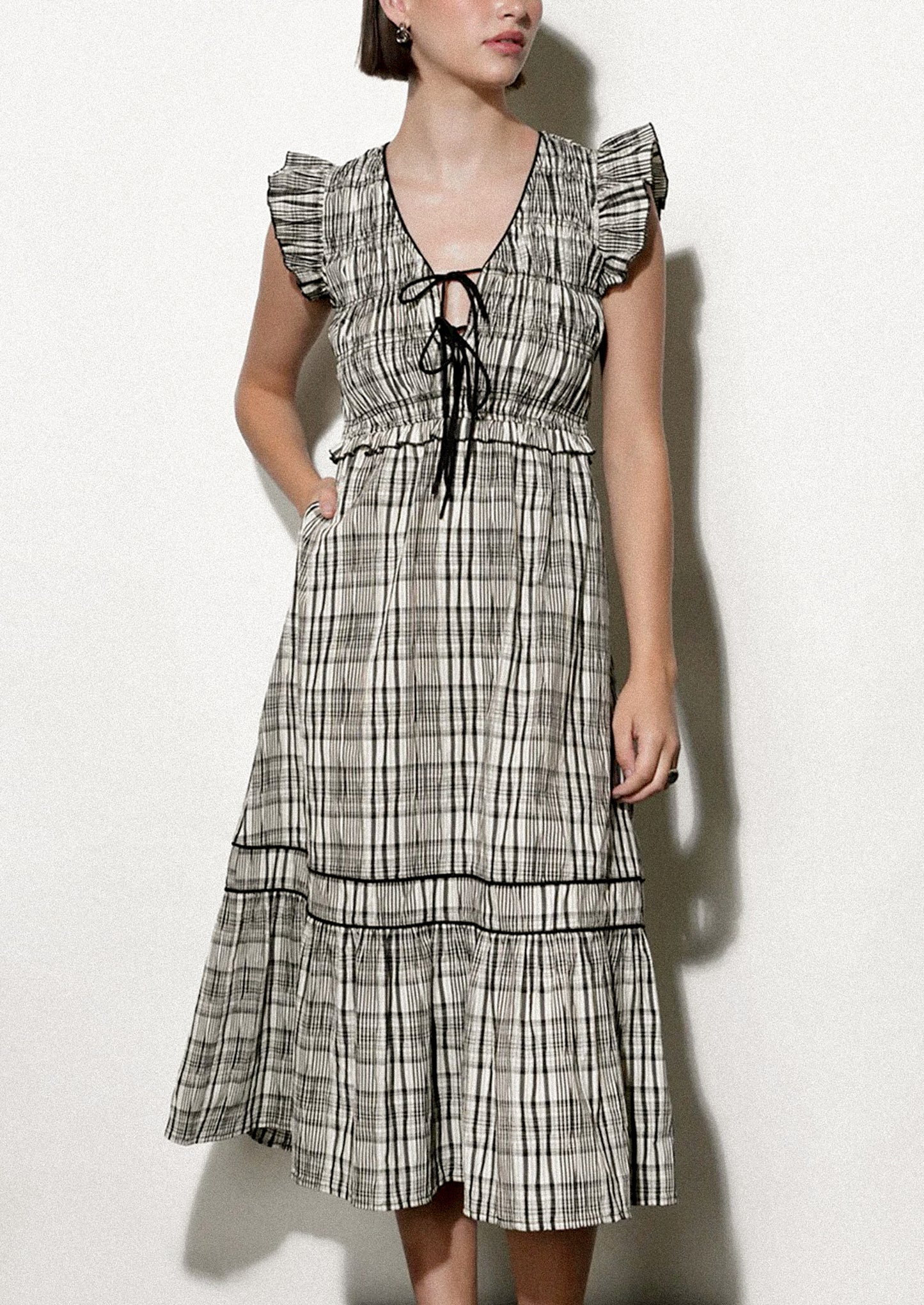 Woman wearing a black and white plaid dress against a white background.