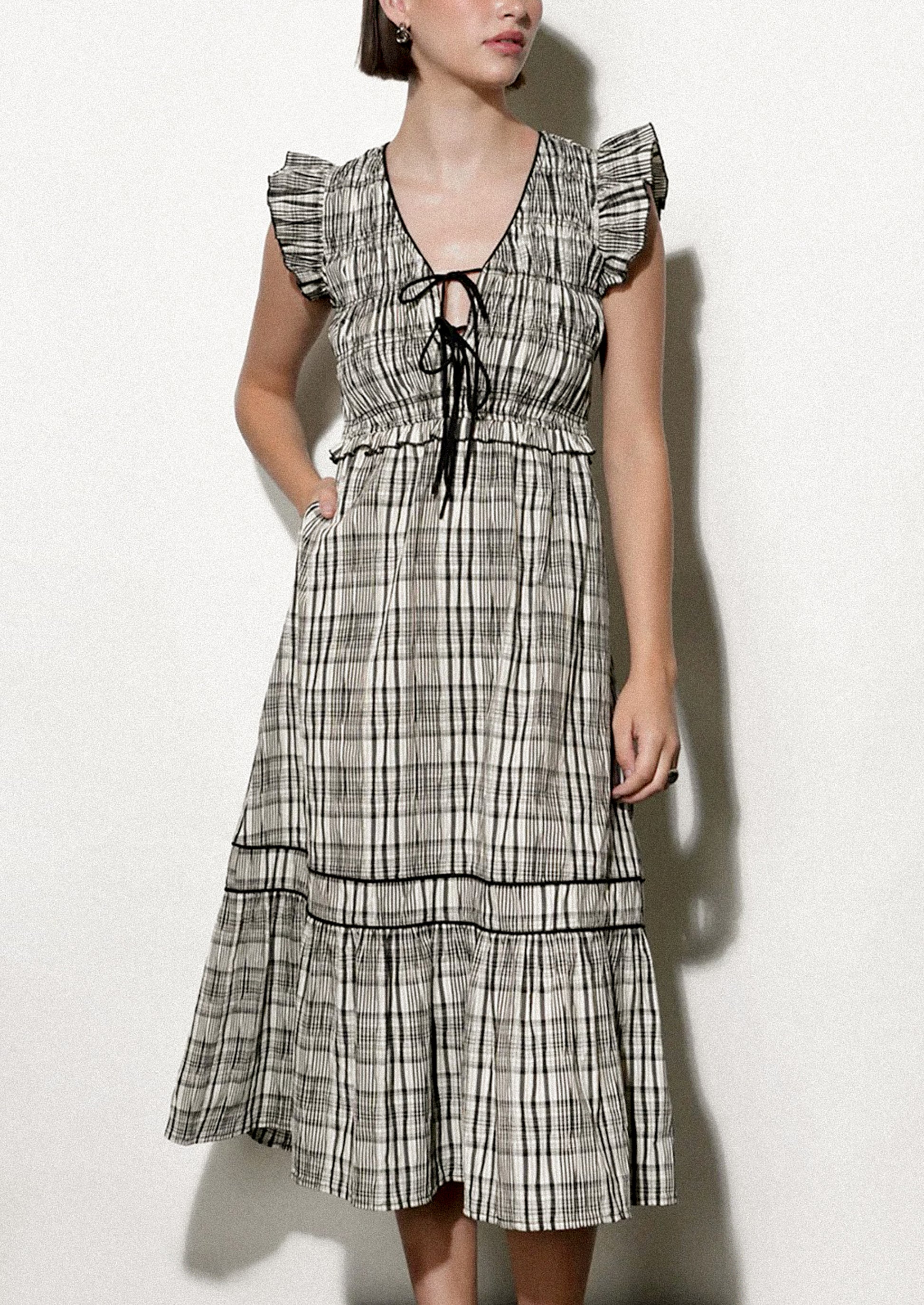 Woman wearing a black and white plaid dress against a white background.