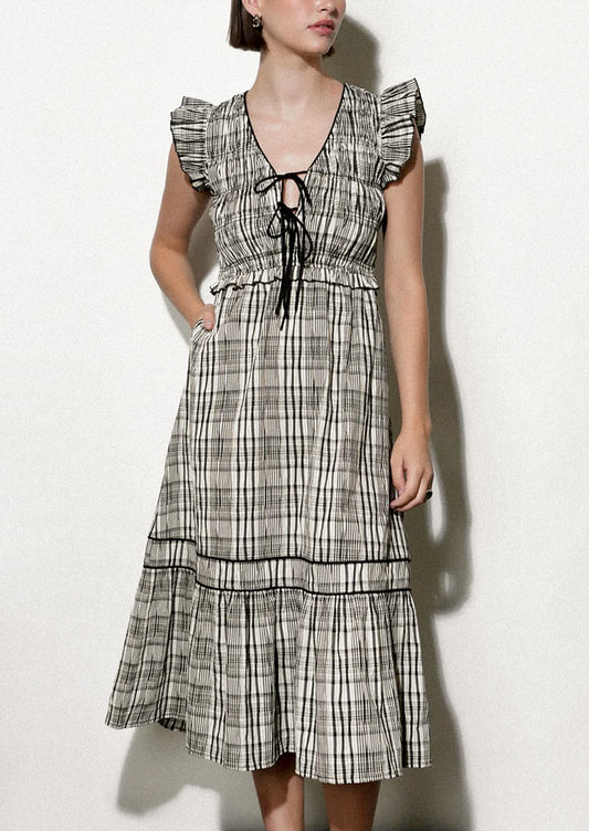 Woman wearing a black and white plaid dress against a white background.