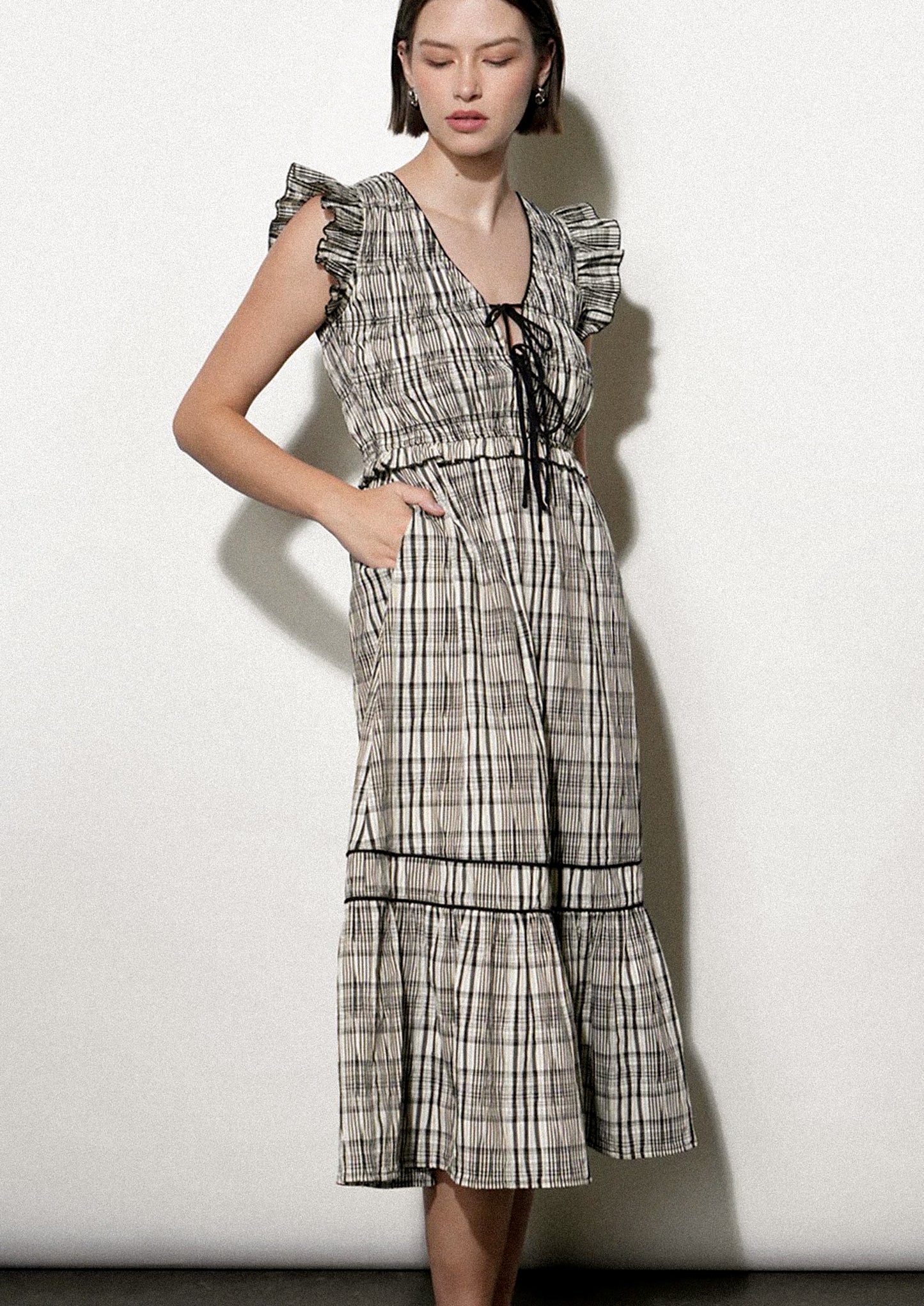 Woman wearing a black and white plaid dress against a white background.