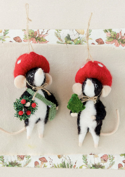 Wool felt ornaments of moles wearing toadstool hats and holding a wreath and a small tree, respectively.