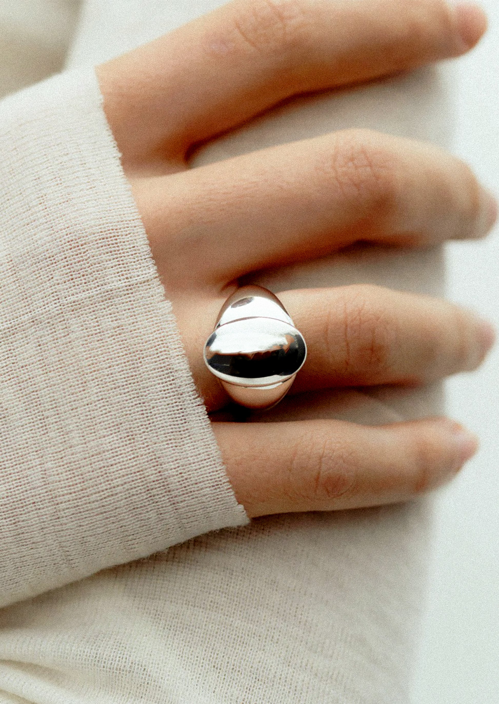 Silver ring on a finger with a neutral background