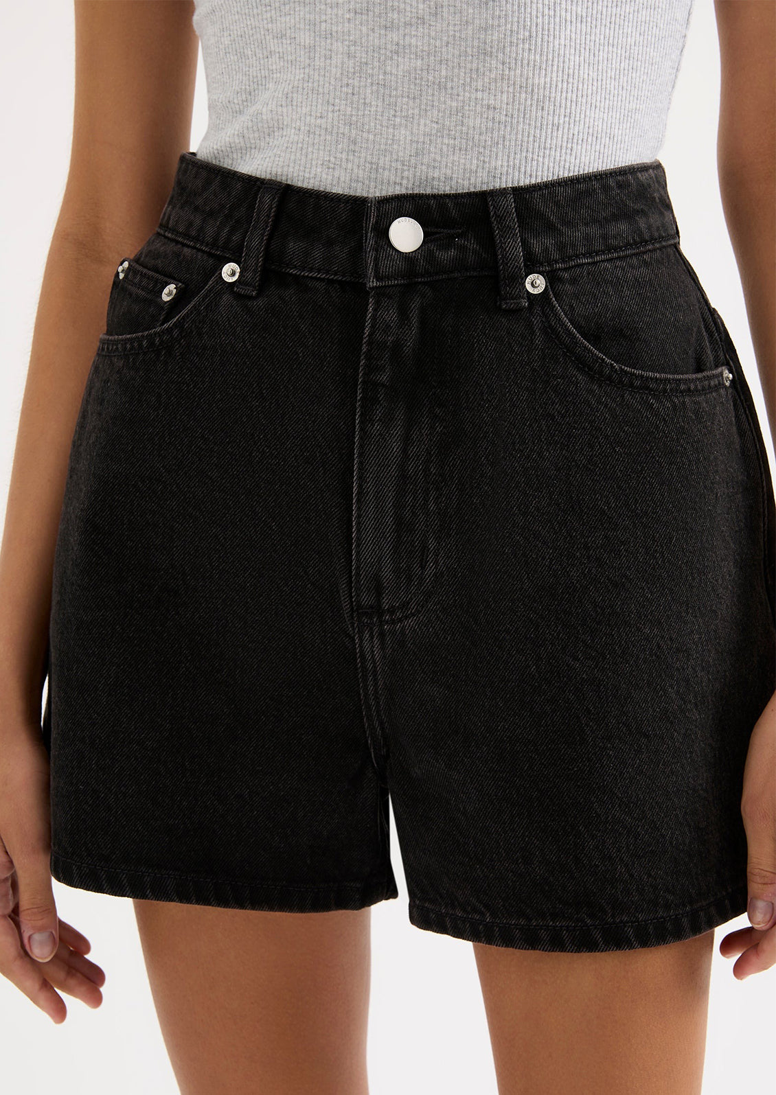 A person wearing a pair of black stonewashed denim shorts.
