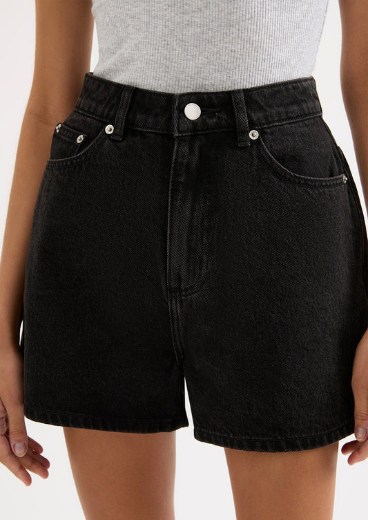 A person wearing a pair of black stonewashed denim shorts.