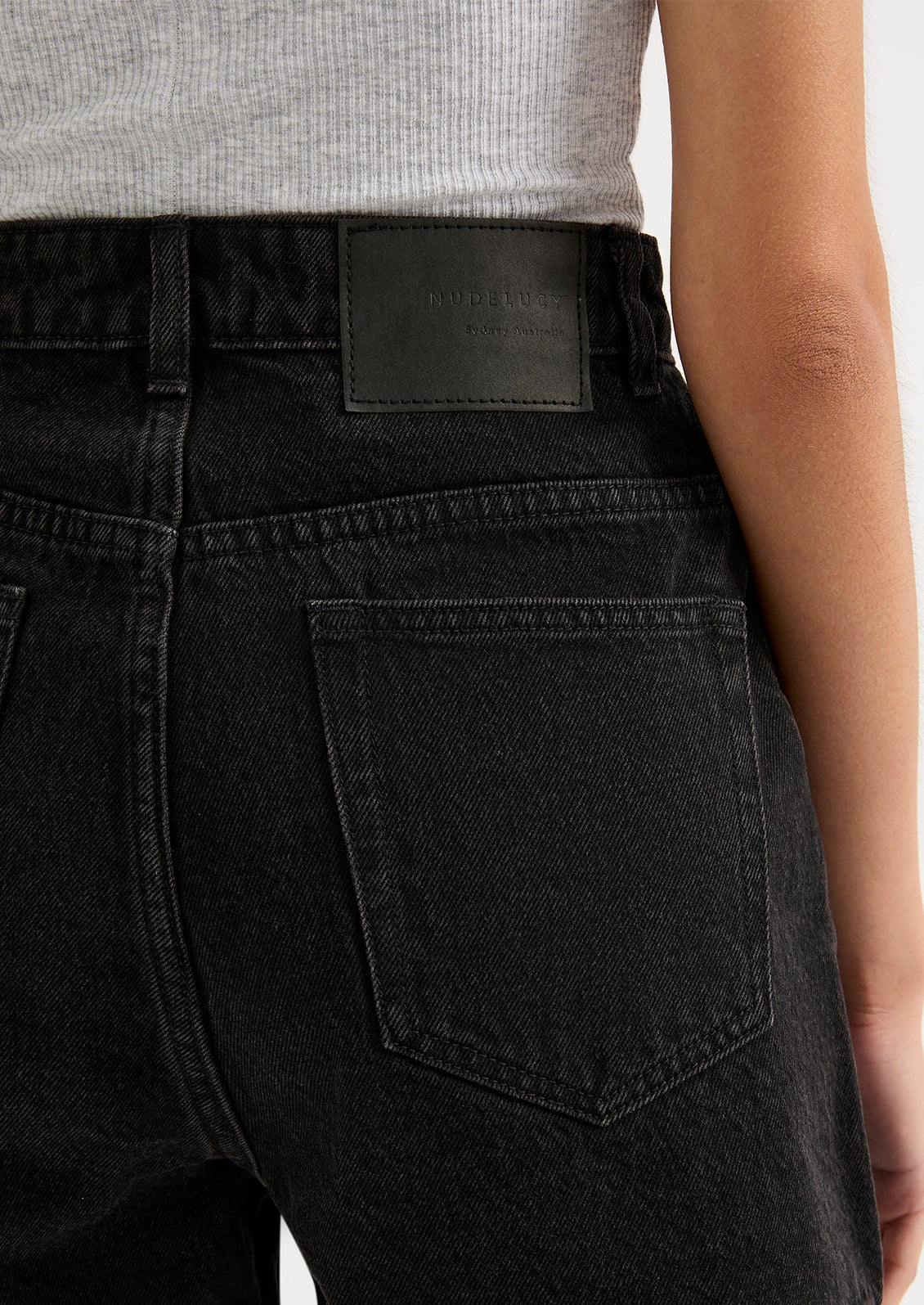 A person wearing a pair of black stonewashed denim shorts.