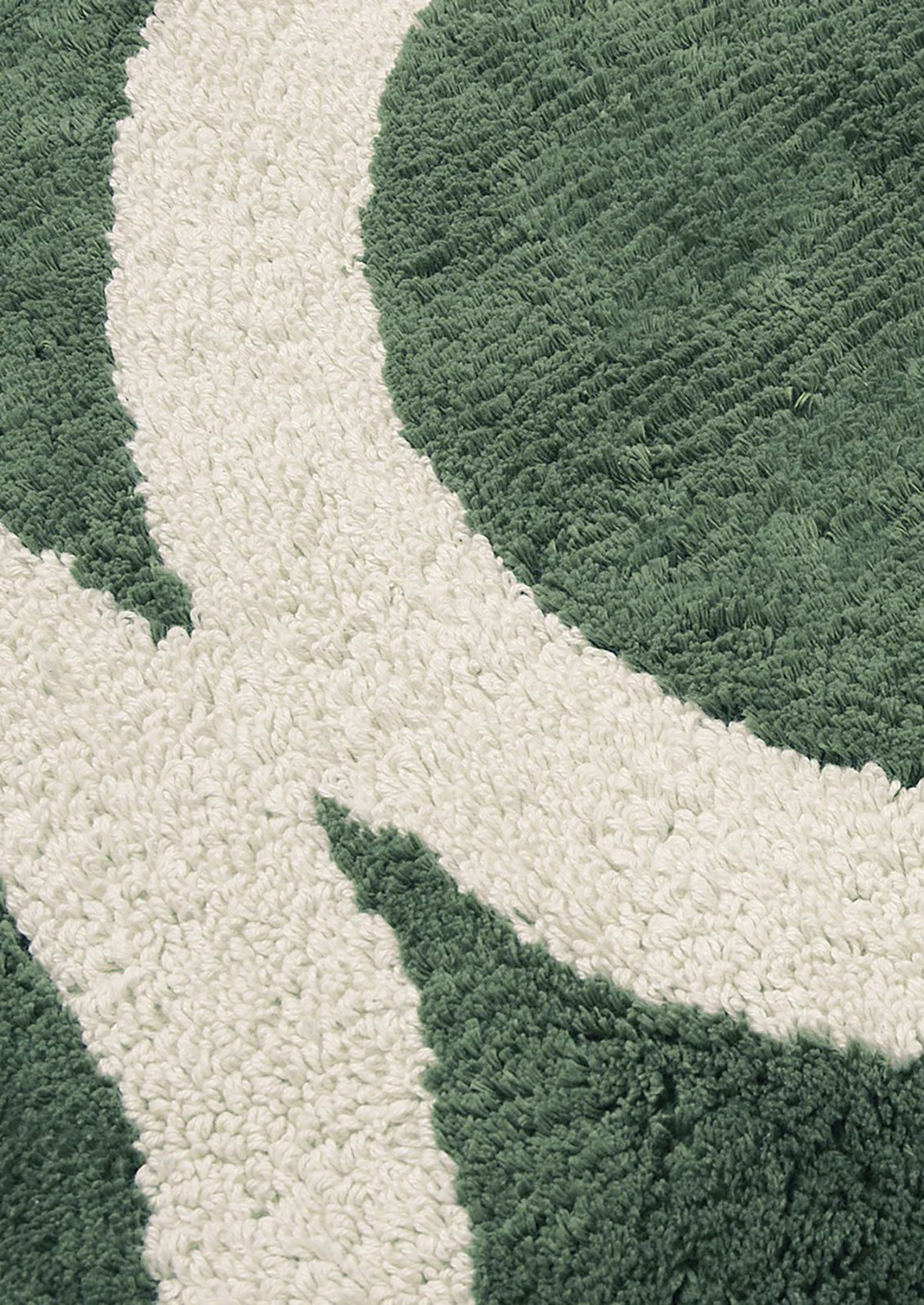 Close-up of a textured green and white rug with leaf patterns.