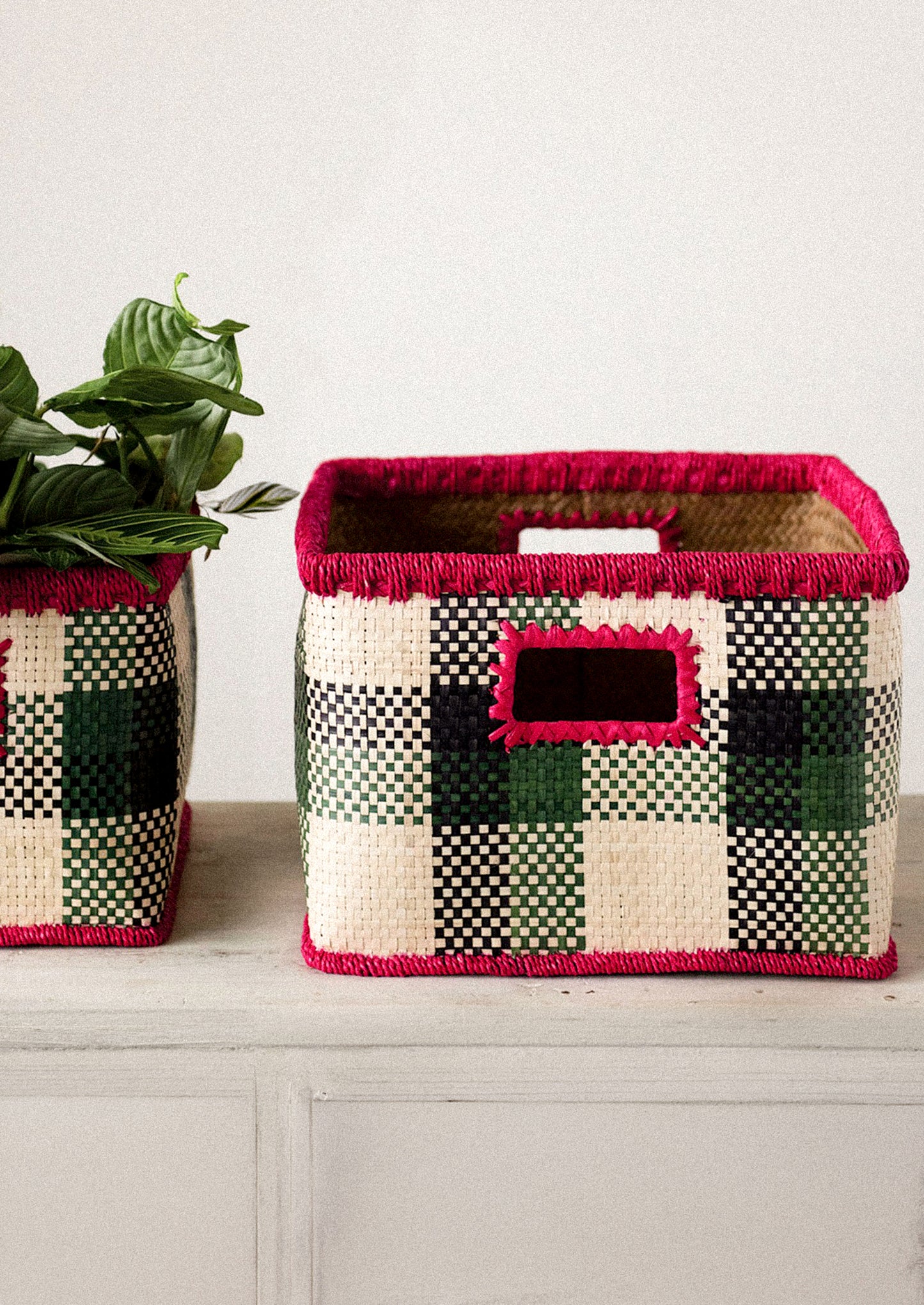 Two woven baskets with a checkered pattern on a wooden surface.