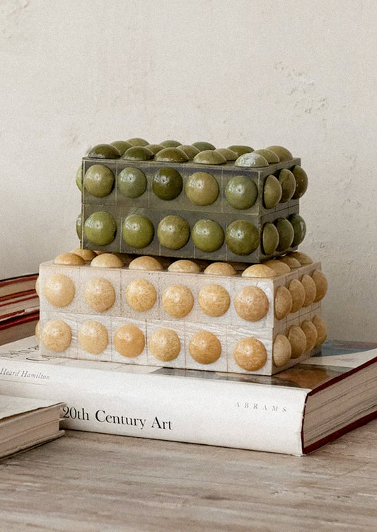 Decorative boxes with hobnail texture stacked on top of each other on a book.