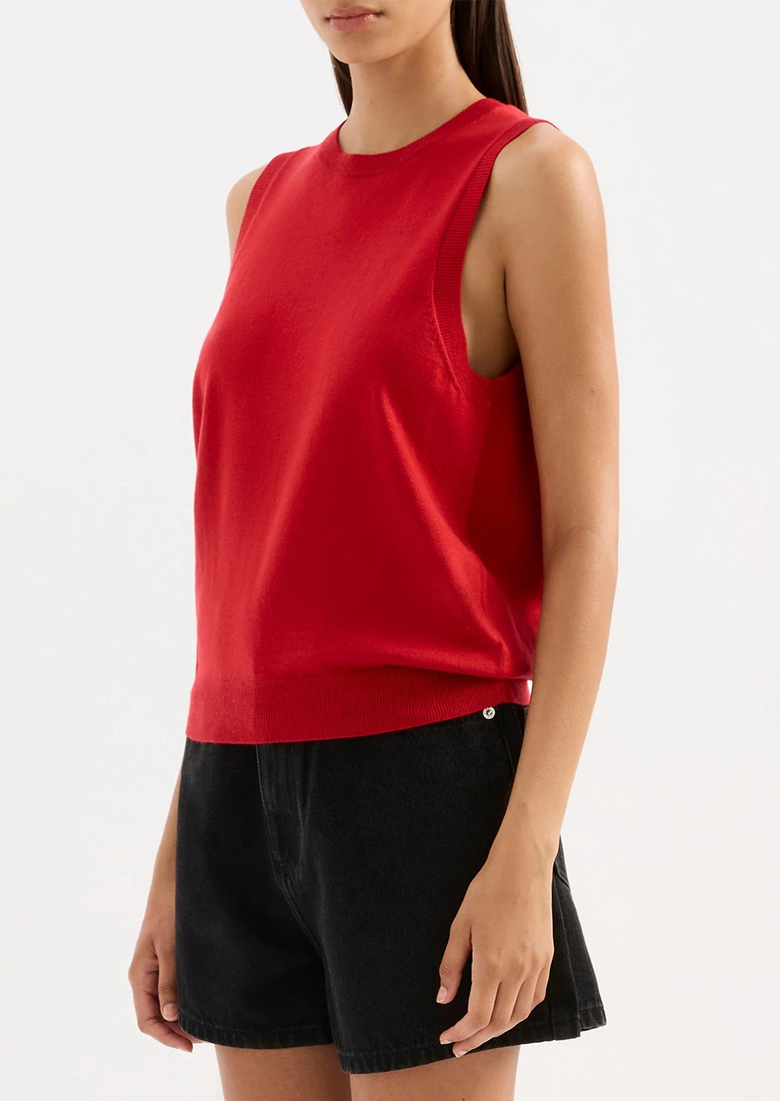 Person wearing a red sleeveless top and black shorts on a white background