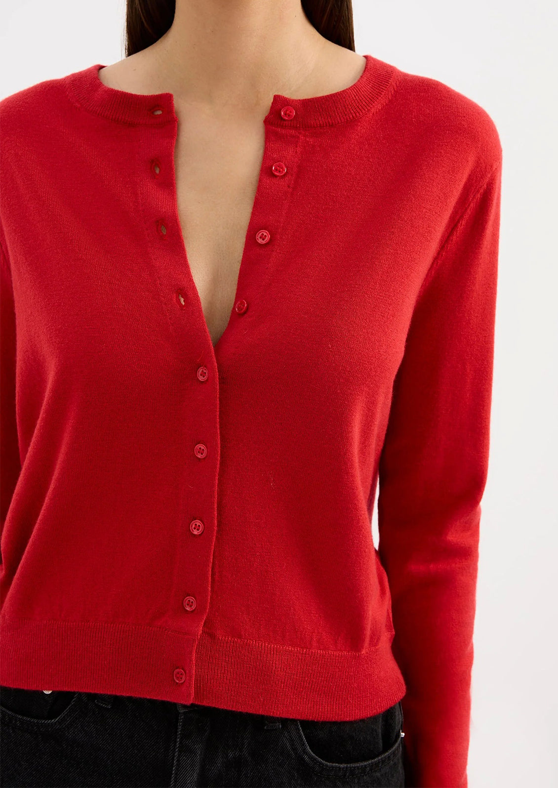 Red cardigan worn by a person on a white background