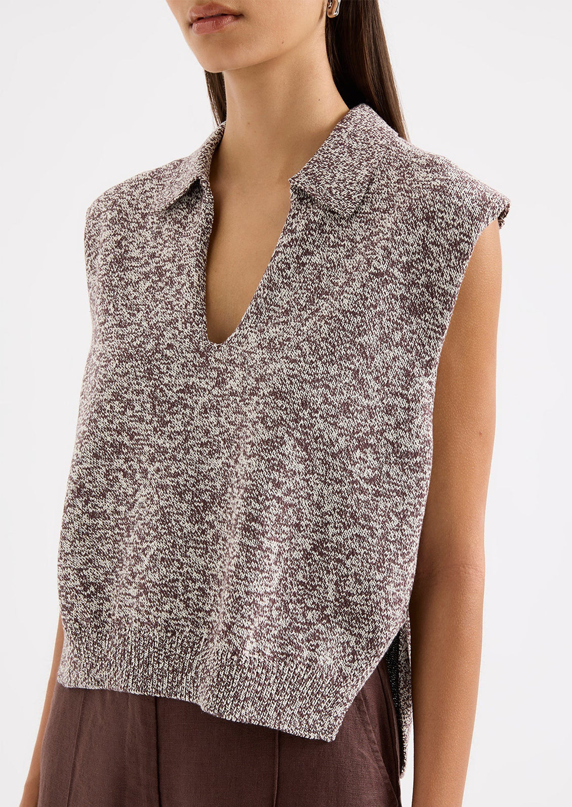 Woman wearing a sleeveless knitted top with a plain background